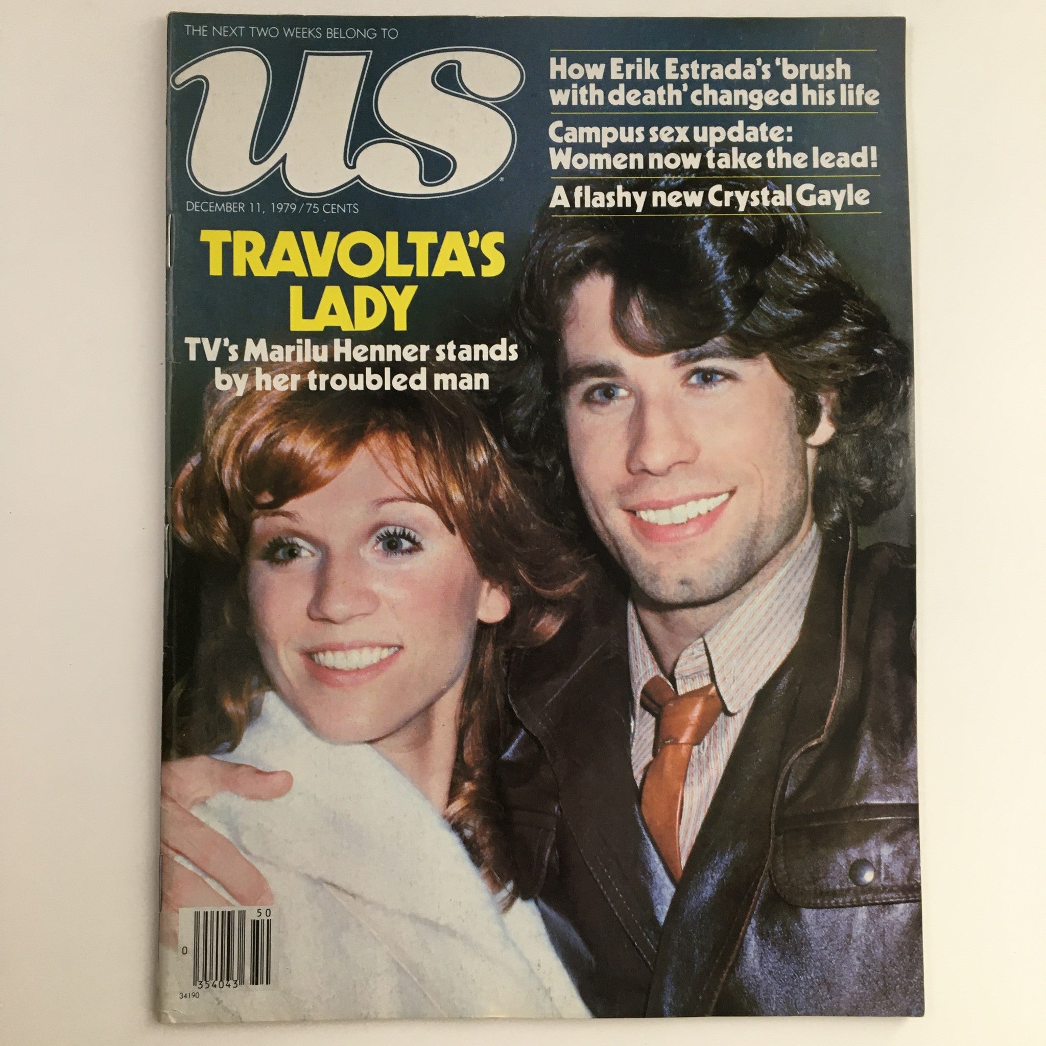 US Magazine cover from December 11, 1979 featuring John Travolta and Marilu Henner. The title reads 'Travolta's Lady - TV's Marilu Henner stands by her troubled man.' The magazine showcases classic 1970s pop culture and is in good, vintage condition.