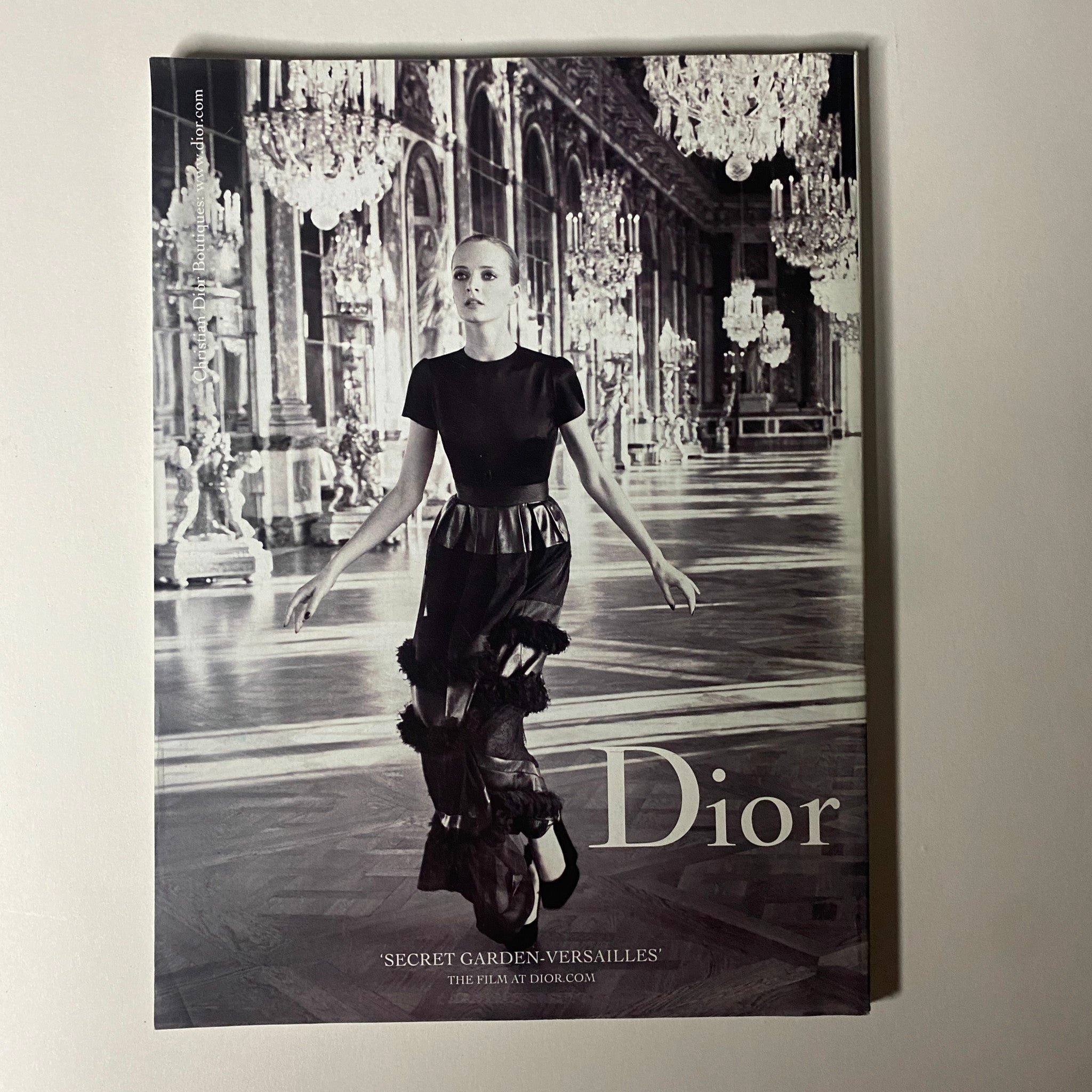 Dior advertisement featuring a model in an elegant outfit, shot in the historic setting of Versailles, part of the 'Secret Garden' campaign, seen in Vogue Magazine August 2012.