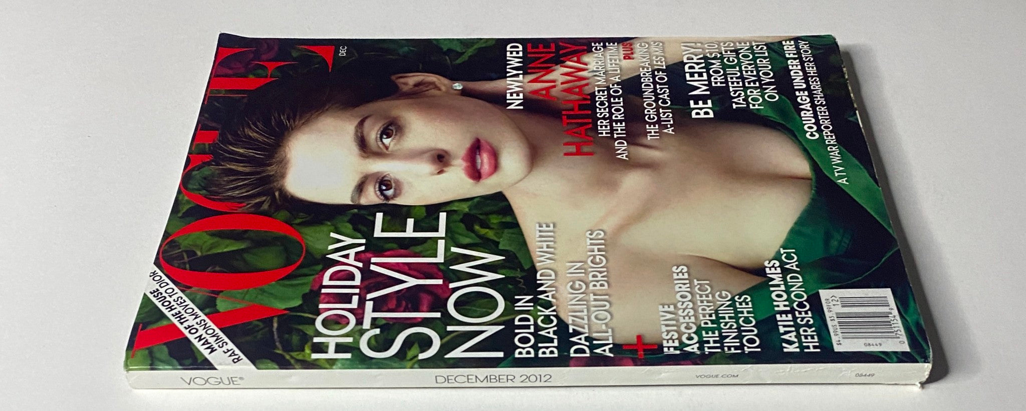 Vogue Magazine December 2012 Anne Hathaway Cover shown at an angle with lush greenery background, emphasizing seasonal fashion and Anne Hathaway's style.