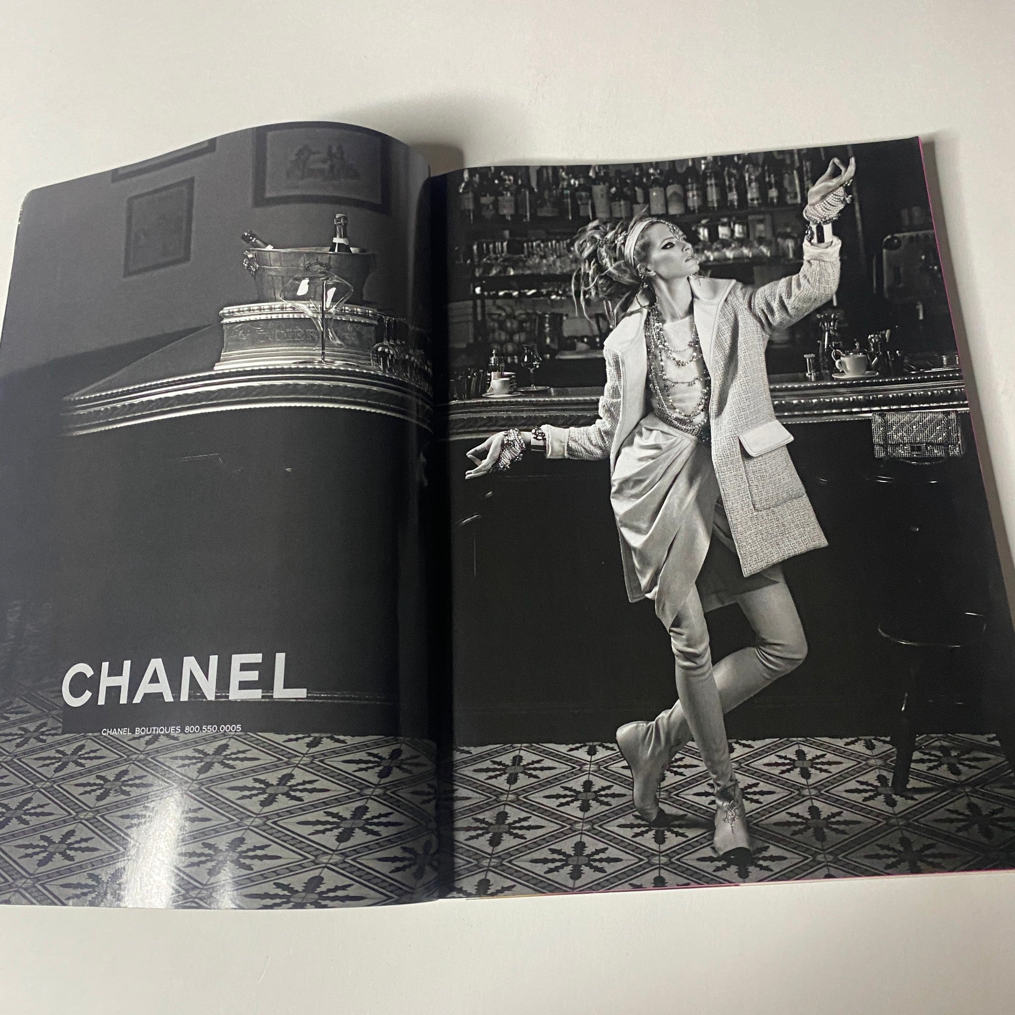 Vogue Magazine June 2012 presenting a Chanel advertisement with a model in a chic outfit dancing in a vintage bar setting. The photograph emphasizes high fashion in a sophisticated ambiance.