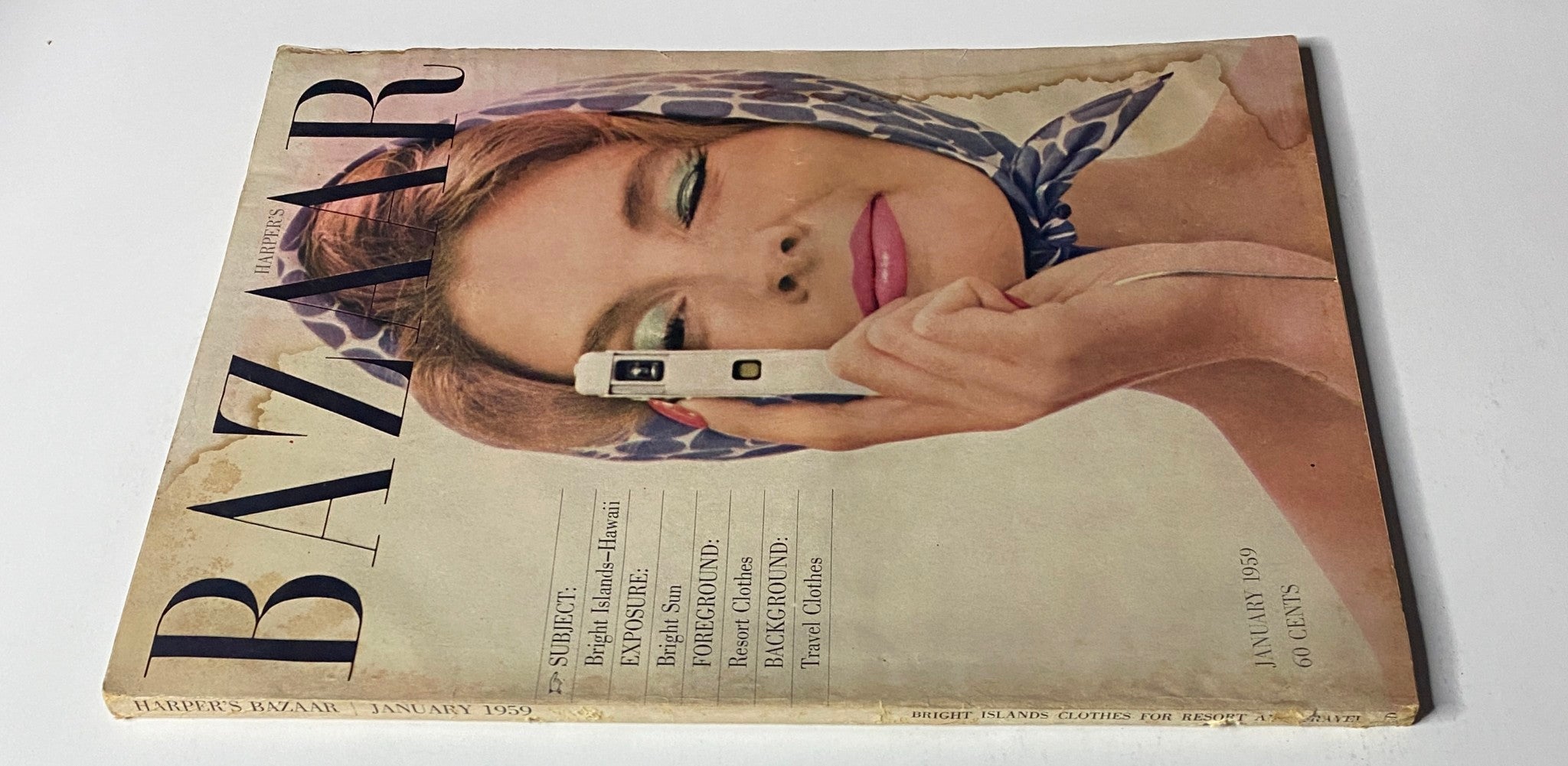 Side view of the cover of Harper's Bazaar Magazine January 1959 showcasing a woman holding a camera, with the title Bright Islands - Hawaii.