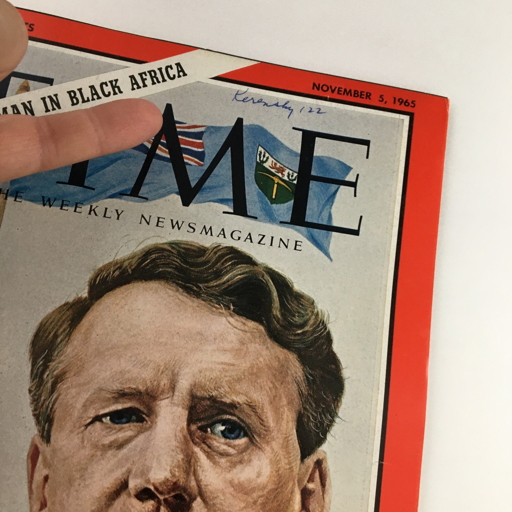 Close-up of Time Magazine November 5 1965 cover highlighting the title 'The White Man in Black Africa' with a finger pointing at the text, showcasing the magazine's vintage condition.