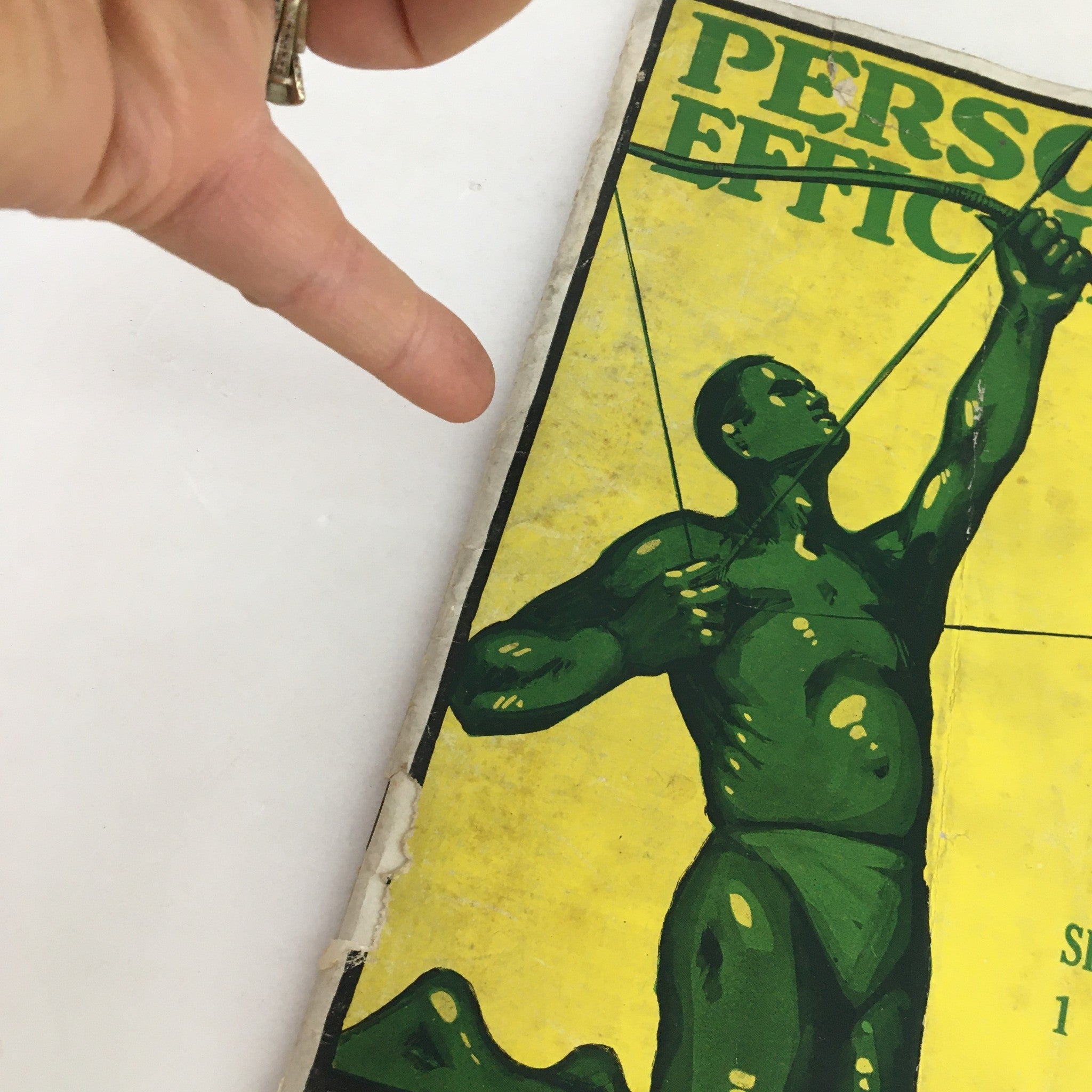 Close-up of the cover of Personal Efficiency Magazine September 1919, showing a green figure aiming an arrow, with visible wear and details from the vintage publication.