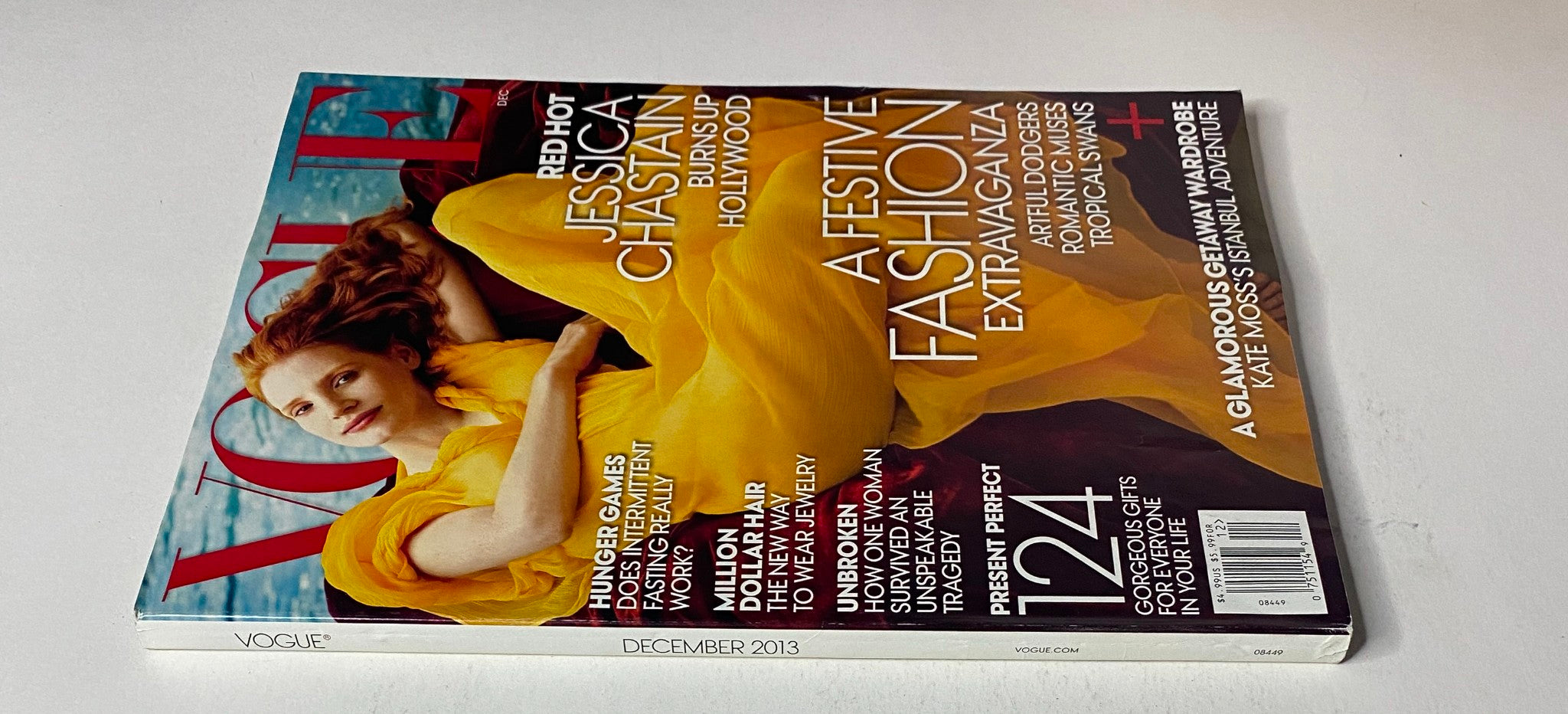 Cover of Vogue Magazine December 2013 featuring Jessica Chastain in a flowing yellow dress, highlighting festive fashion extravaganza and winter glamour.