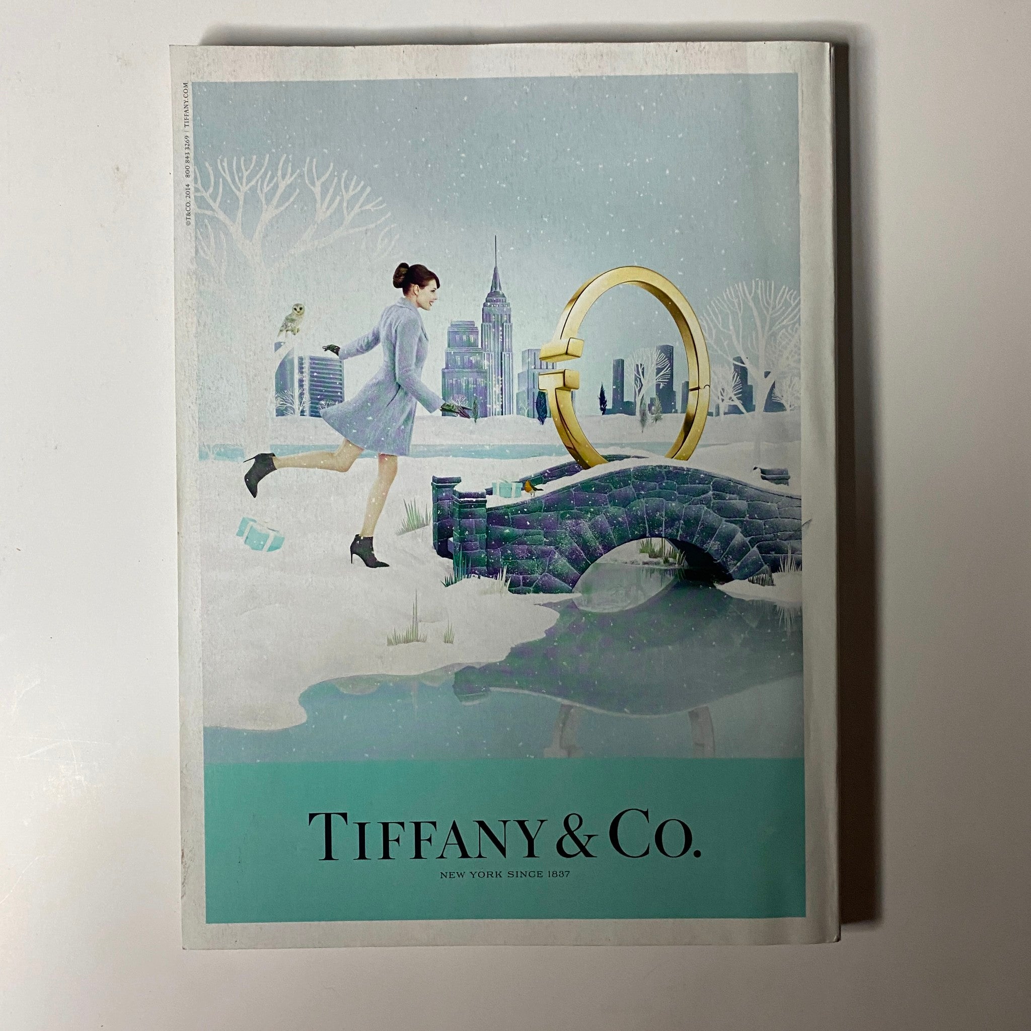 Advertisement from Vogue Magazine December 2014 for Tiffany & Co., featuring a whimsical illustration of a woman in a snowy landscape.