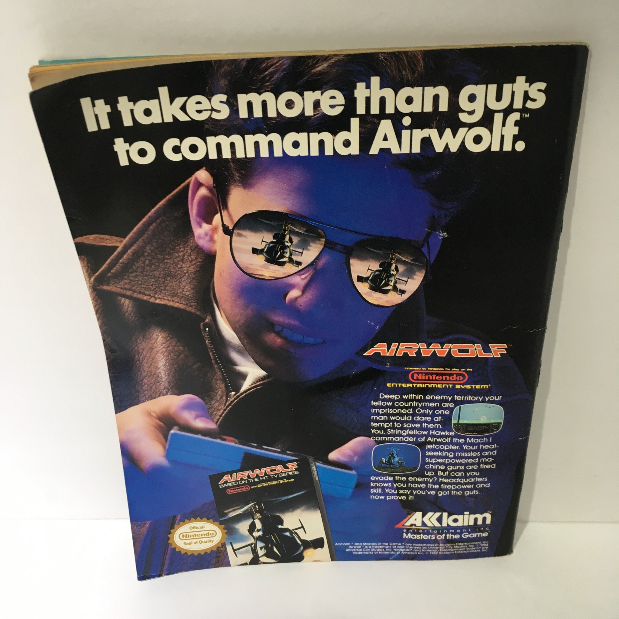Vintage advertisement featuring a boy in sunglasses promoting the Airwolf video game for the Nintendo Entertainment System. The tagline reads, 'It takes more than guts to command Airwolf.' Captivating design from the 1980s.