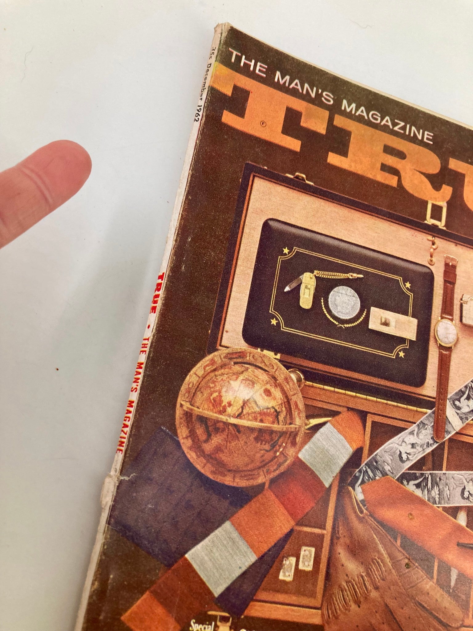 Side view of TRUE The Man's Magazine December 1962, showcasing the magazine's spine and cover design. The title 'Never Trust A Woman with a Charge Account' is prominently featured with artistic graphics and vintage aesthetics.