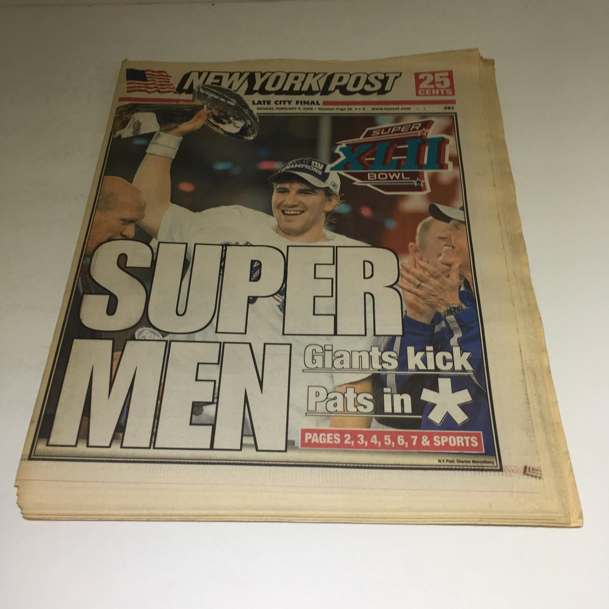 New York Post front page from February 4, 2008, featuring the headline 'Super Men Giants kick Pats in'. The image showcases the celebration of the New York Giants victory with a trophy in the background.
