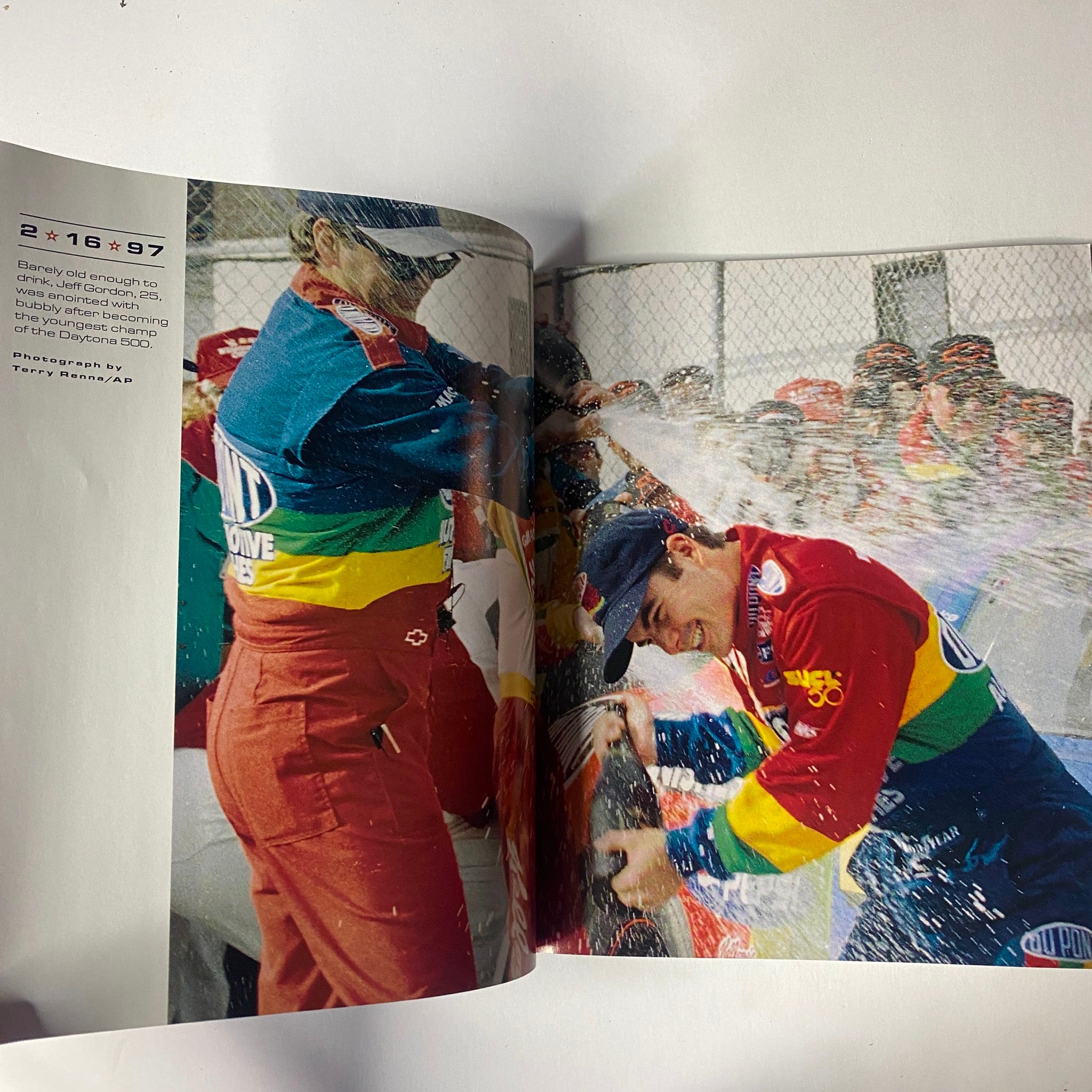 Sports Illustrated Magazine - Tiger Woods YEAR IN PICTURES 1997 captures a celebratory moment in NASCAR, featuring a victorious driver spraying champagne after a major race.