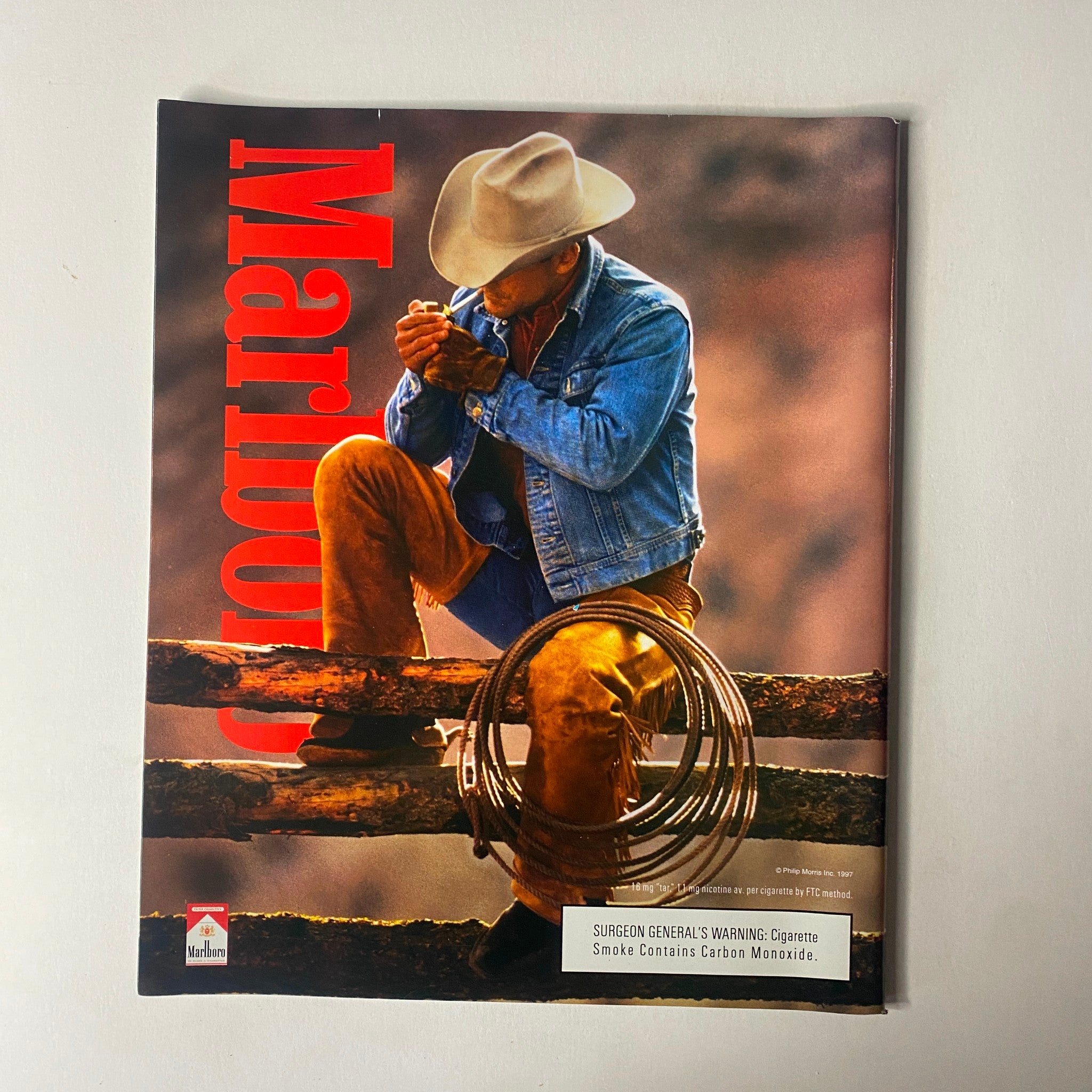 Sports Illustrated Magazine - Tiger Woods YEAR IN PICTURES 1997 displaying a cowboy in a reflective pose, engaging with his lasso, embodying themes of rugged Americana.