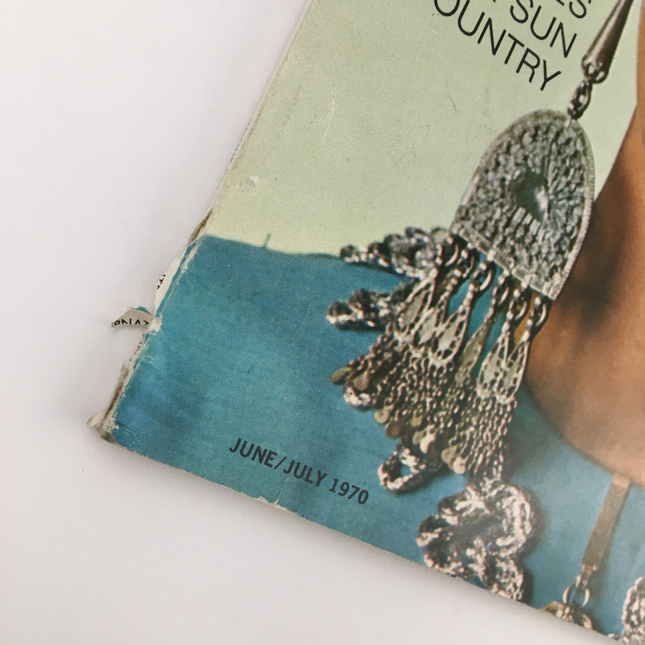 Detail of the edge of International Vogue Pattern Book June 1970, highlighting the bottom text 'JUNE/JULY 1970' and intricate details of the cover model's earrings.
