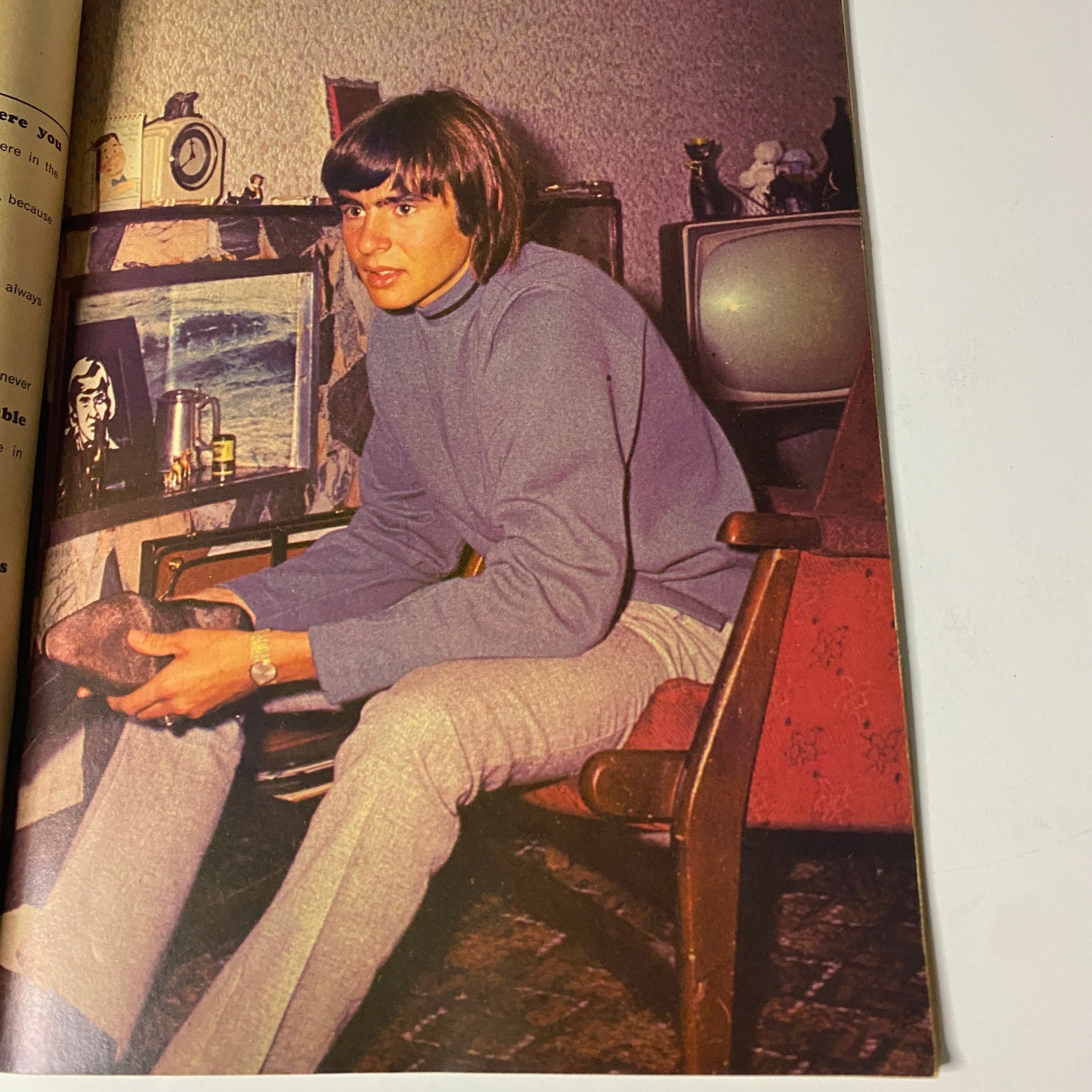 Image from Tiger Beat's Official July 1967 #3 Monkee Spectacular showing a young man sitting on a chair in casual attire, featuring vintage decor in the background.