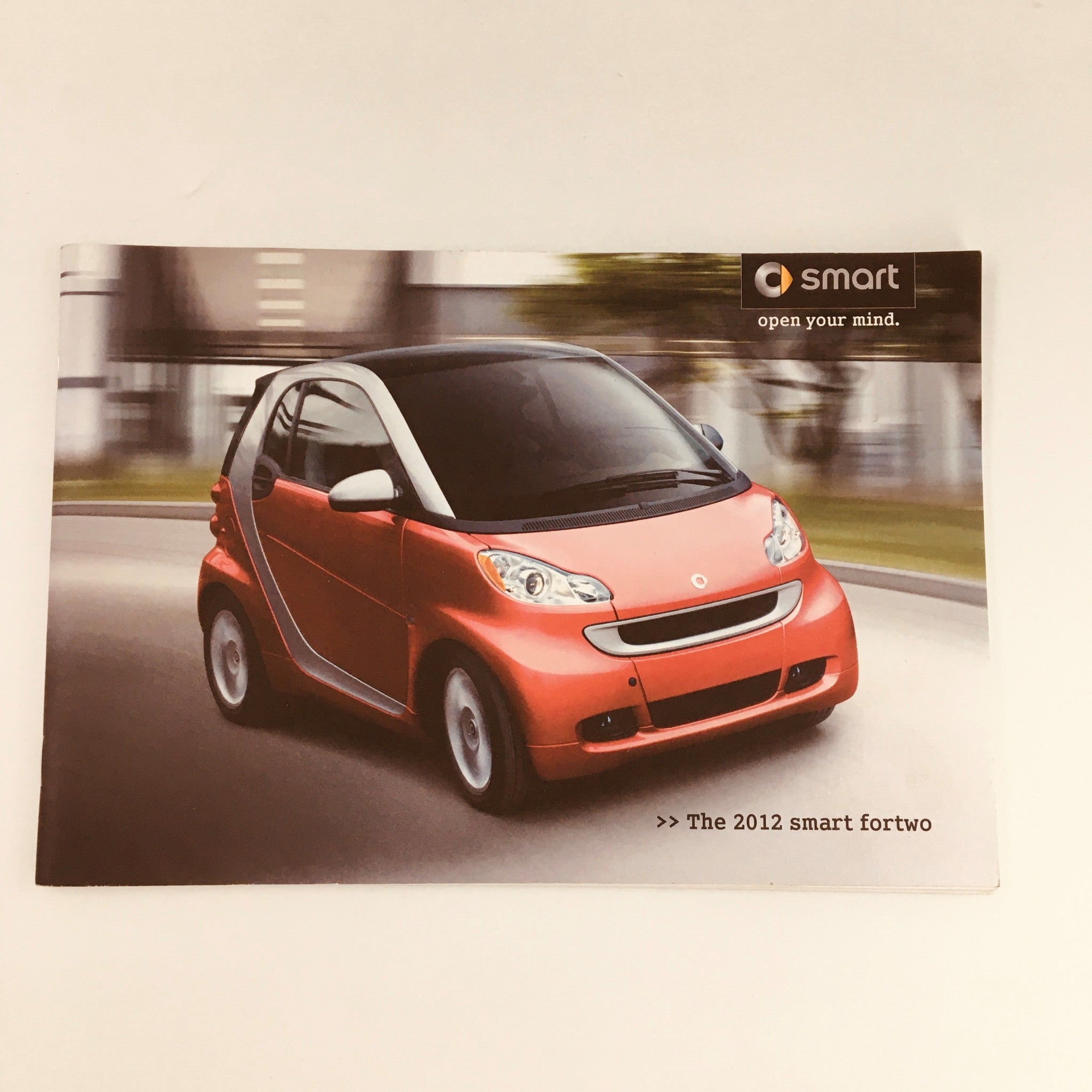 2012 Smart Fortwo City Solution Hill-Start Assist Car Brochure cover featuring a red Smart Fortwo car in motion, promoting the 2012 smart fortwo.