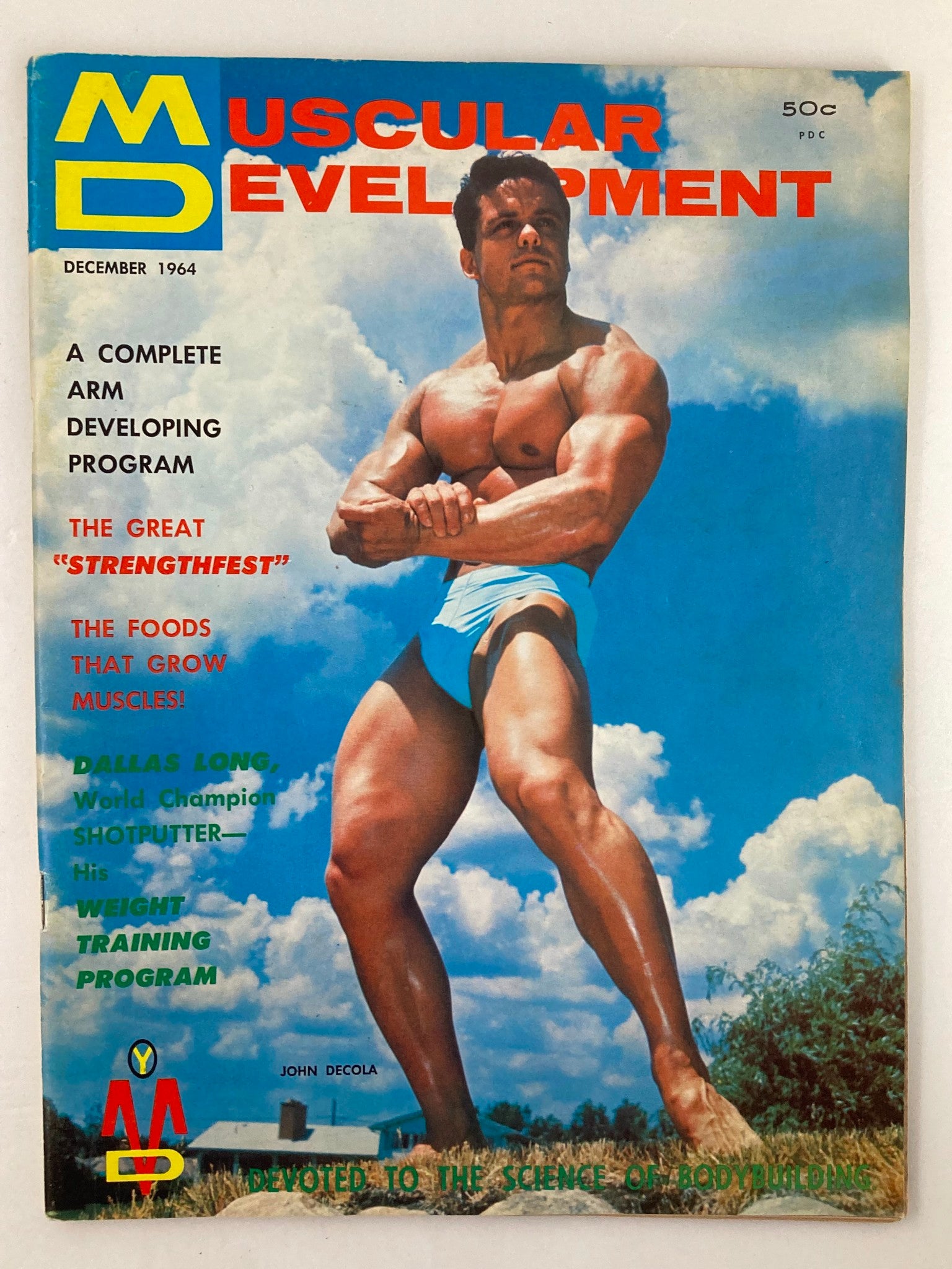 Cover of VTG Muscular Development Magazine December 1964 featuring John Decola, showcasing vintage bodybuilding culture with the headline 'Muscular Development' and vibrant imagery.