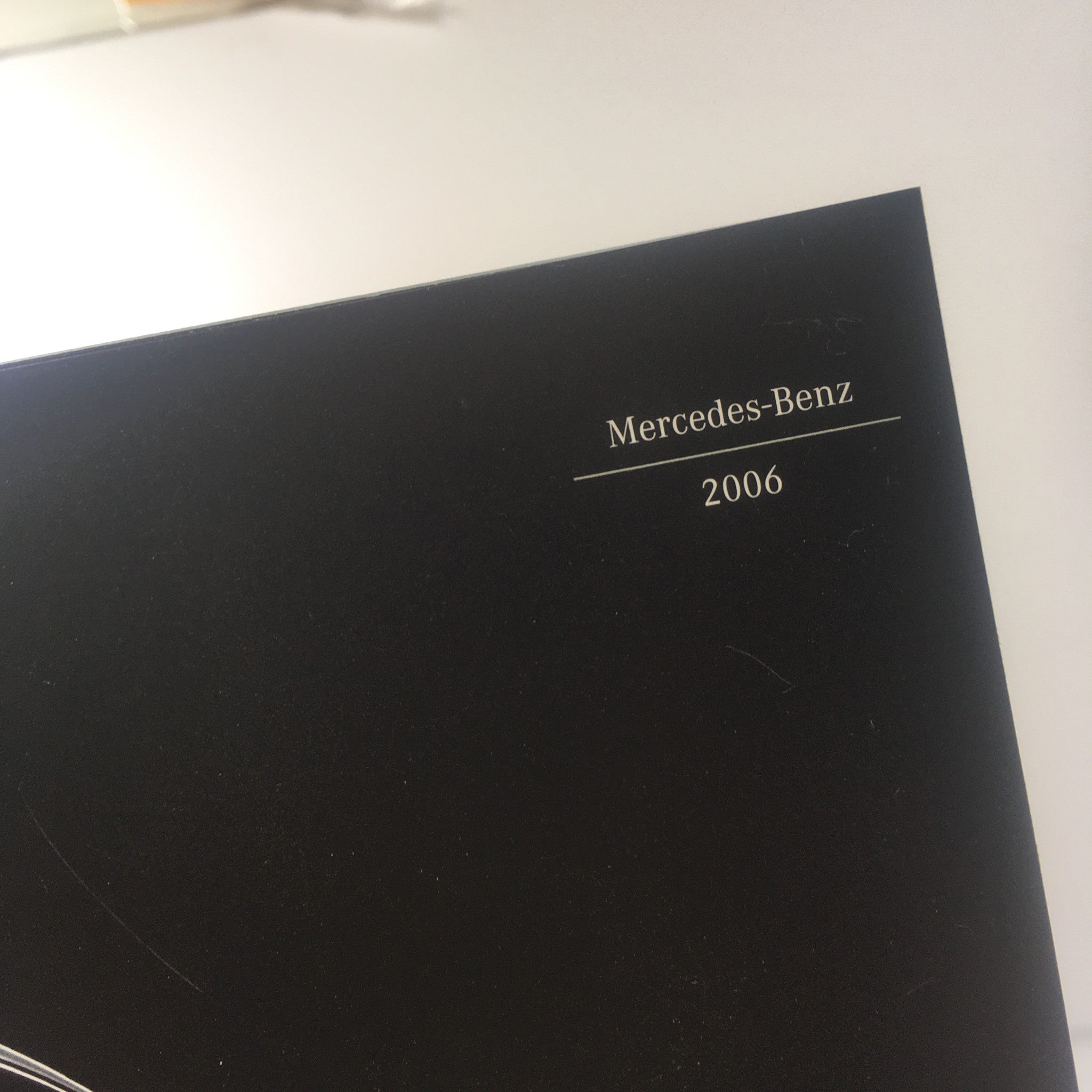Close-up of the 2006 Mercedes-Benz logo featured on the dealership car brochure catalog.