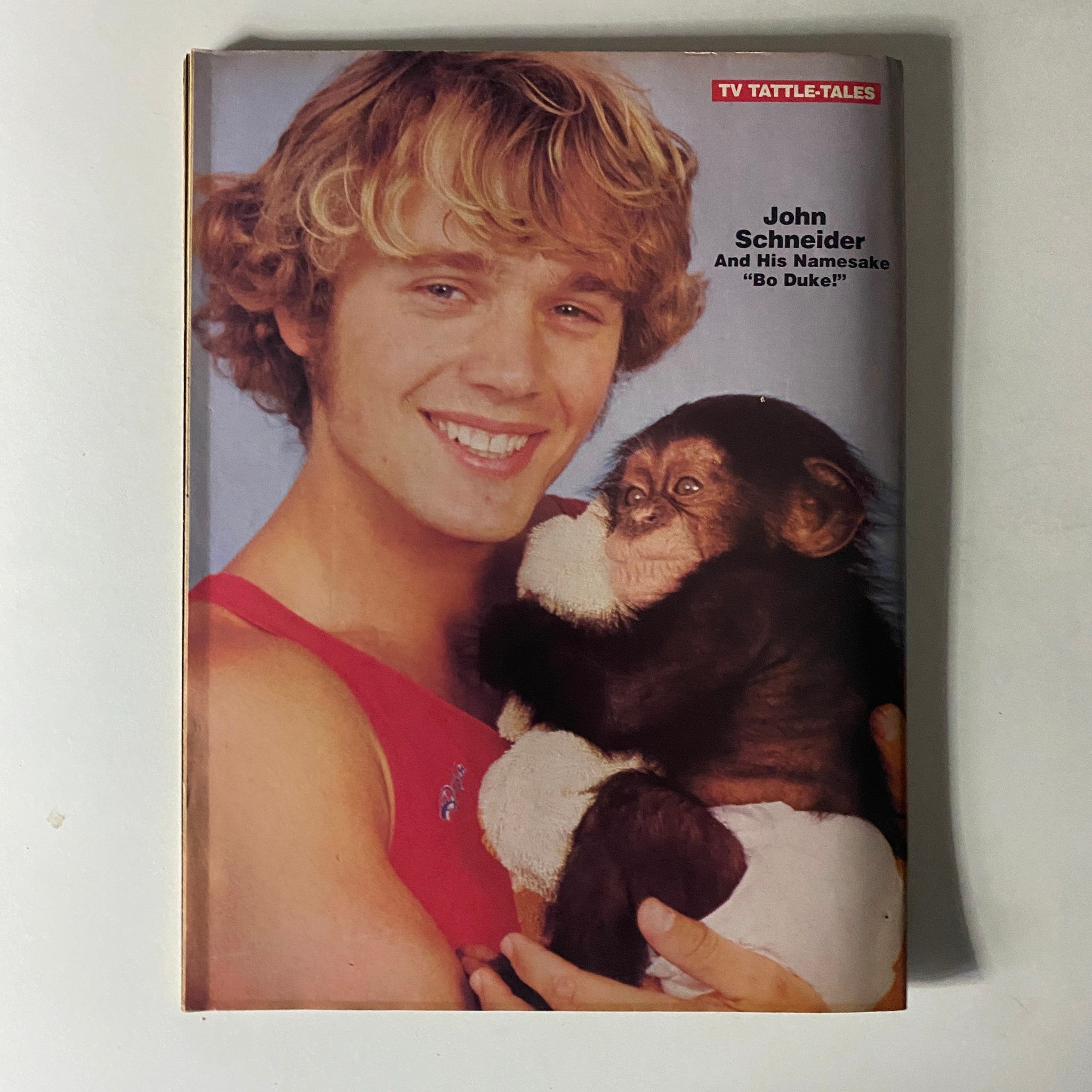 John Schneider with a baby chimpanzee in the Fall 1981 edition of 16 Magazine TV & Movie Tattle-Tales, showcasing a lighthearted moment in celebrity culture.