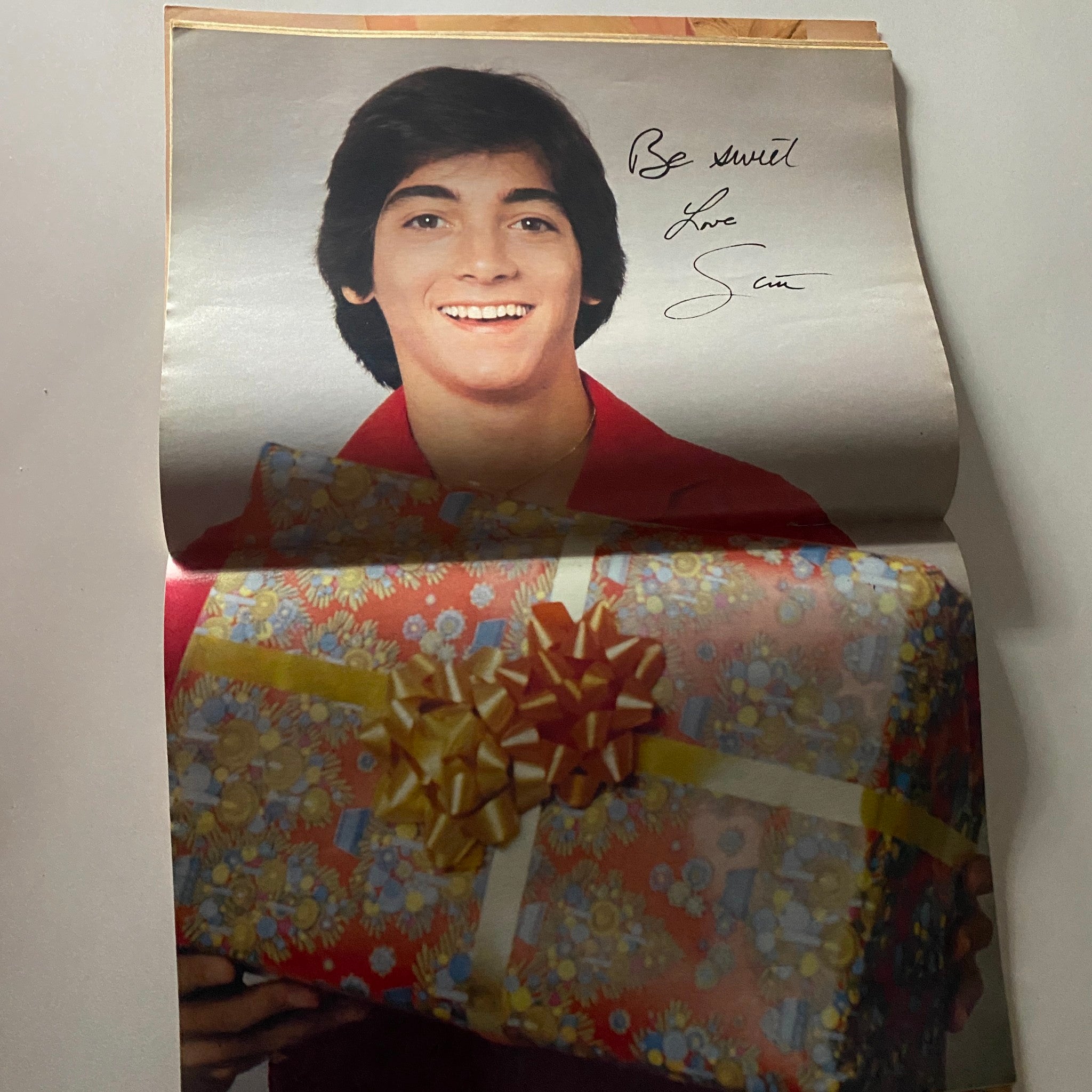 John Schneider photographed in Tiger Beat Magazine January 1982, smiling and holding a wrapped gift.