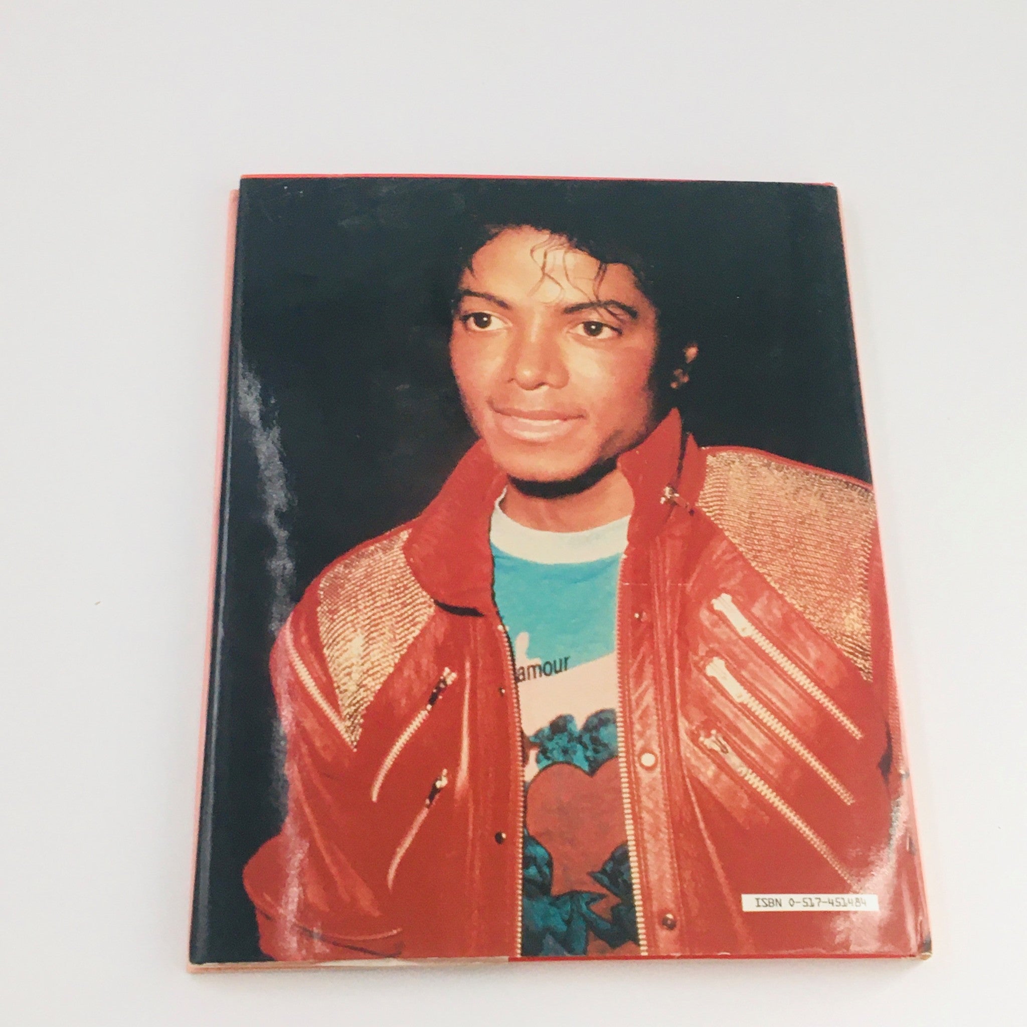 Close-up portrait of Michael Jackson wearing a red jacket, taken from 'Greenwich House 1984 Presents Michael Jackson by Stewart Regan'.