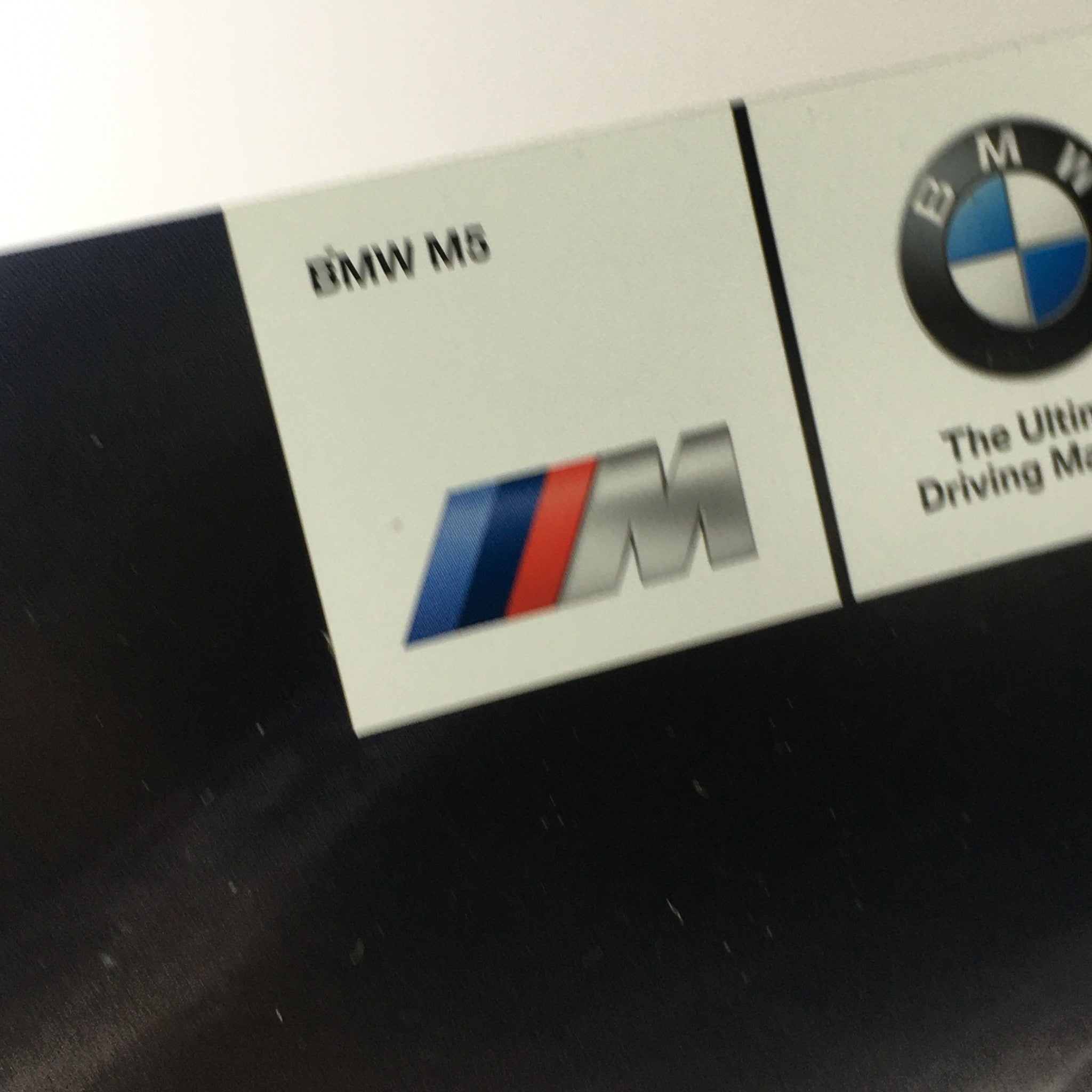 Logo details from the 2014 BMW M5 Dealership Car Auto Brochure Catalog, showcasing the BMW M series emblem.