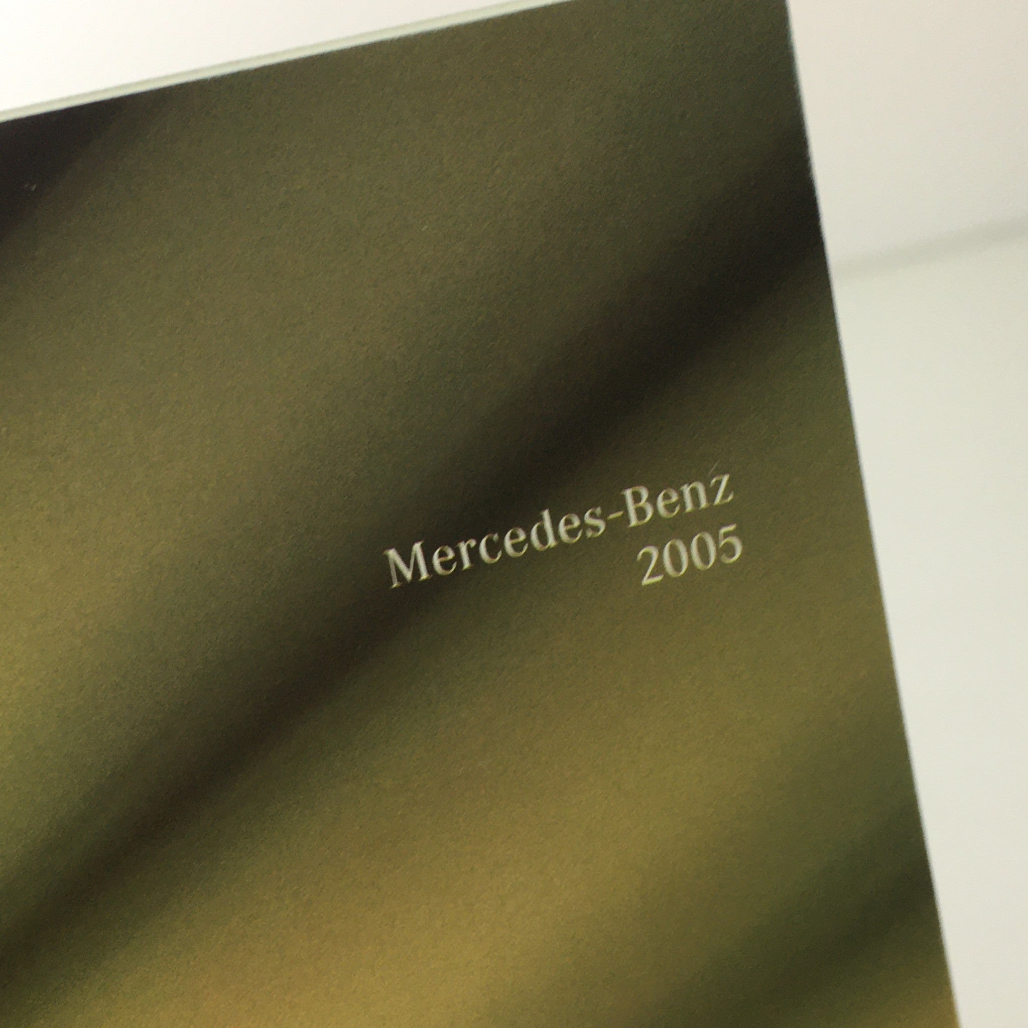 2005 Mercedes-Benz logo on a reflective surface showcasing the branding of the 2005 Mercedes-Benz CLK-Class Dealership Car Auto Brochure Catalog.