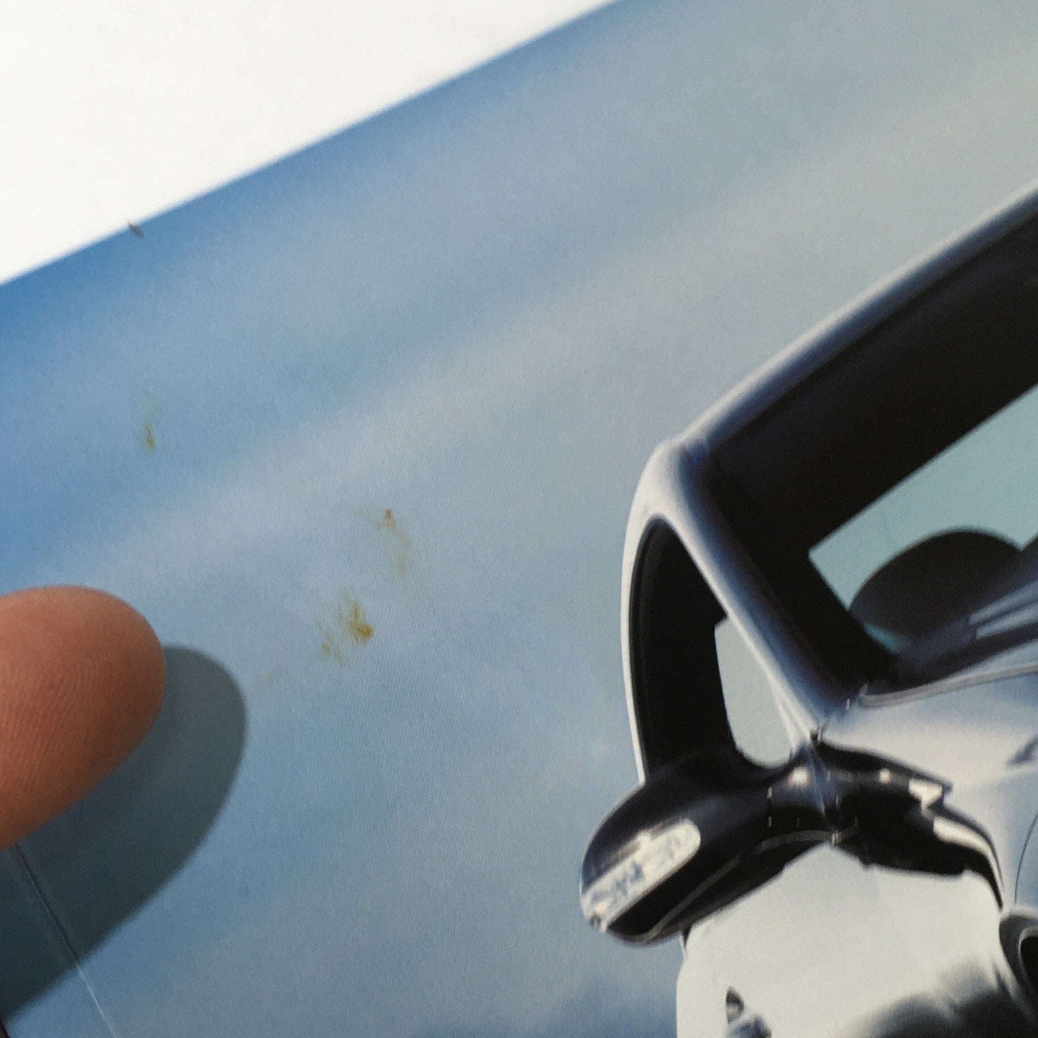 Close-up view of the 2007 Mercedes-Benz CLK-Class 350 550 63 AMG dealership auto brochure cover, showing a hand pointing at the top edge.