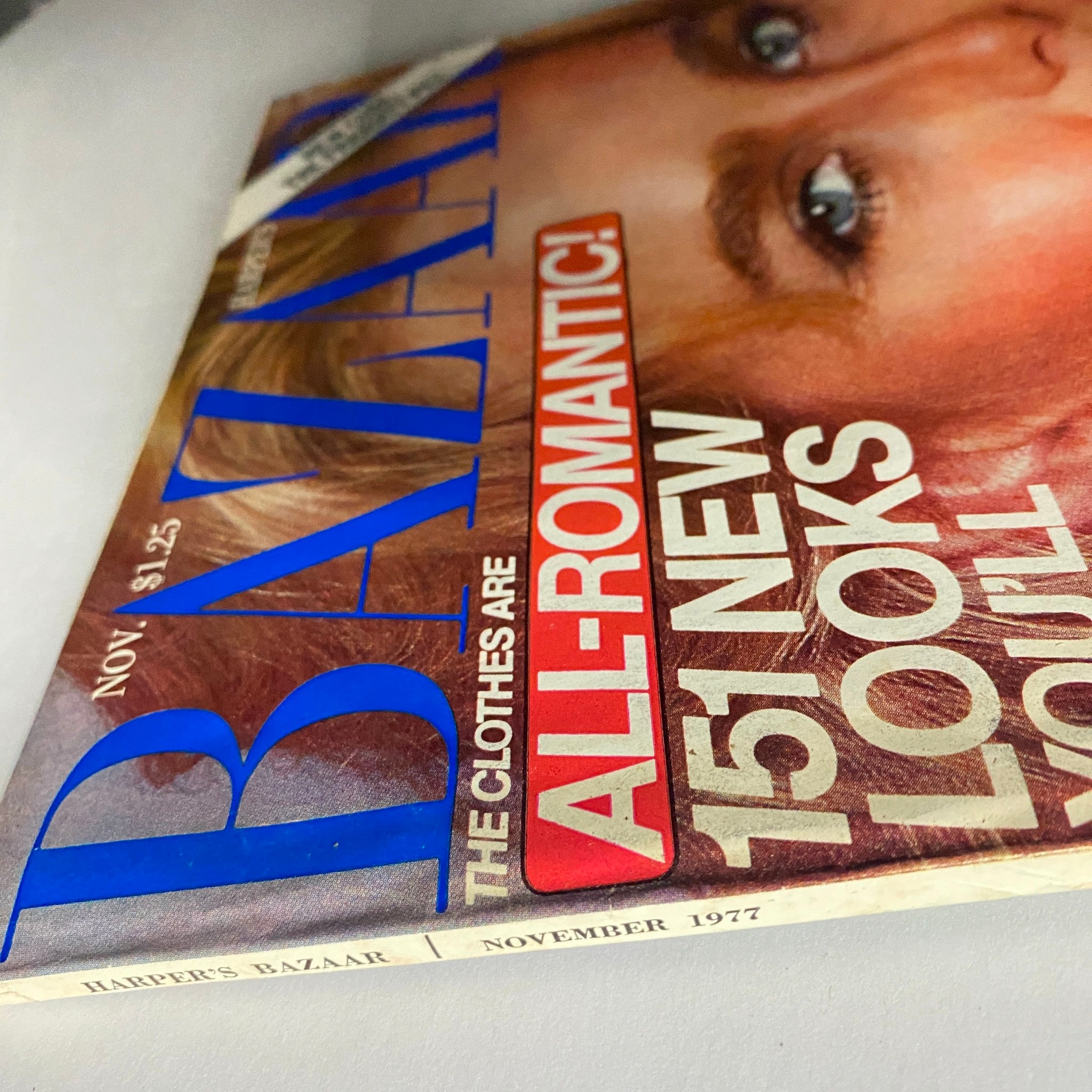 Side view of Harper's Bazaar Magazine November 1977 displaying the magazine title and issue details with a focus on the vibrant blue lettering and the iconic model's face.