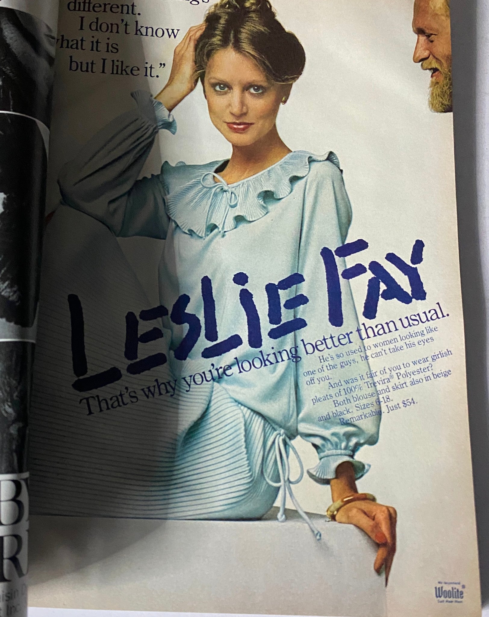 Fashion advertisement from Harper's Bazaar November 1977 showcasing a woman in a light blue outfit with a ruffled neckline, promoting Leslie Fay clothing, emphasizing feminine elegance.