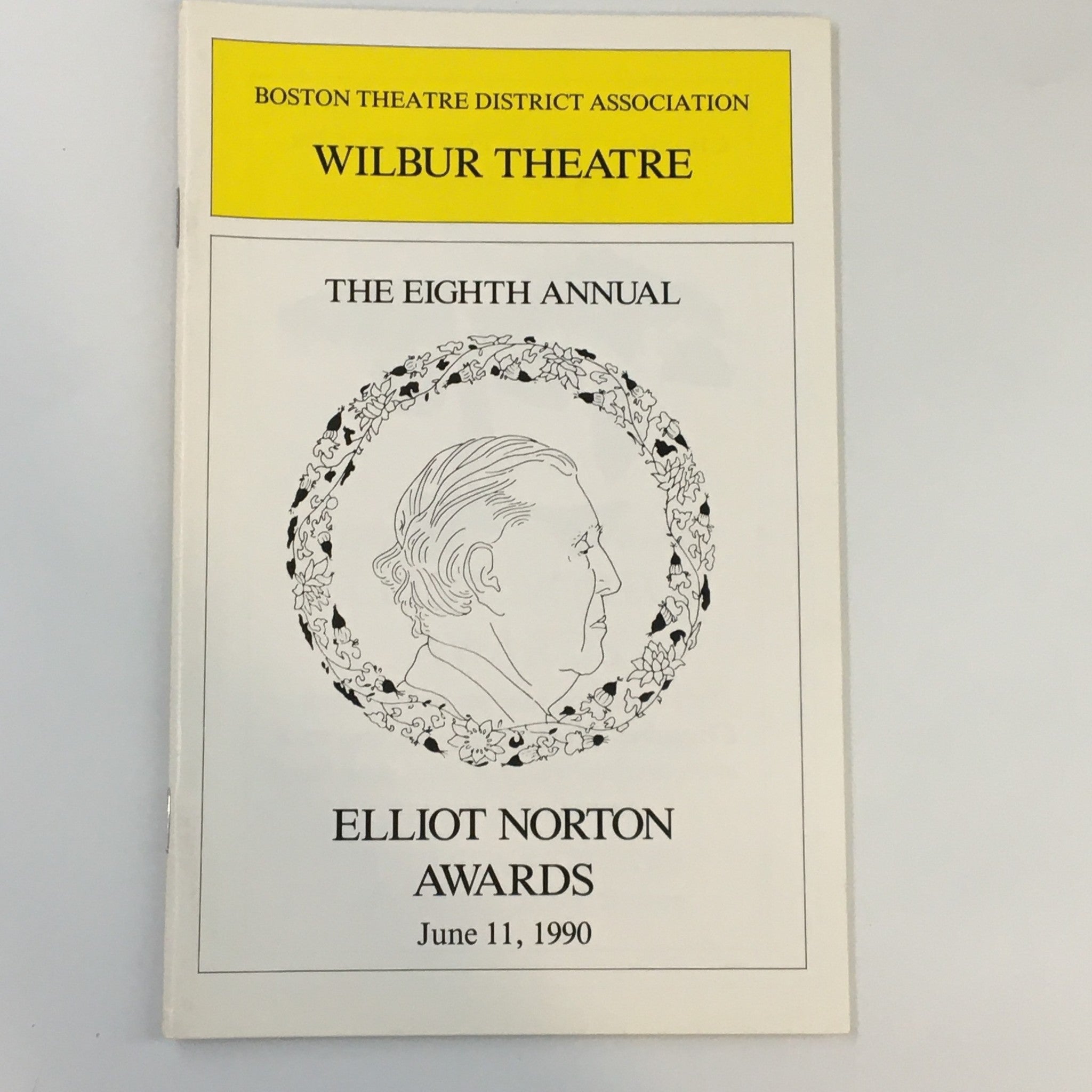 Cover of the 1990 Wilbur Theatre The Eight Annual Elliot Norton Awards program, featuring an illustration of a profile and floral design.