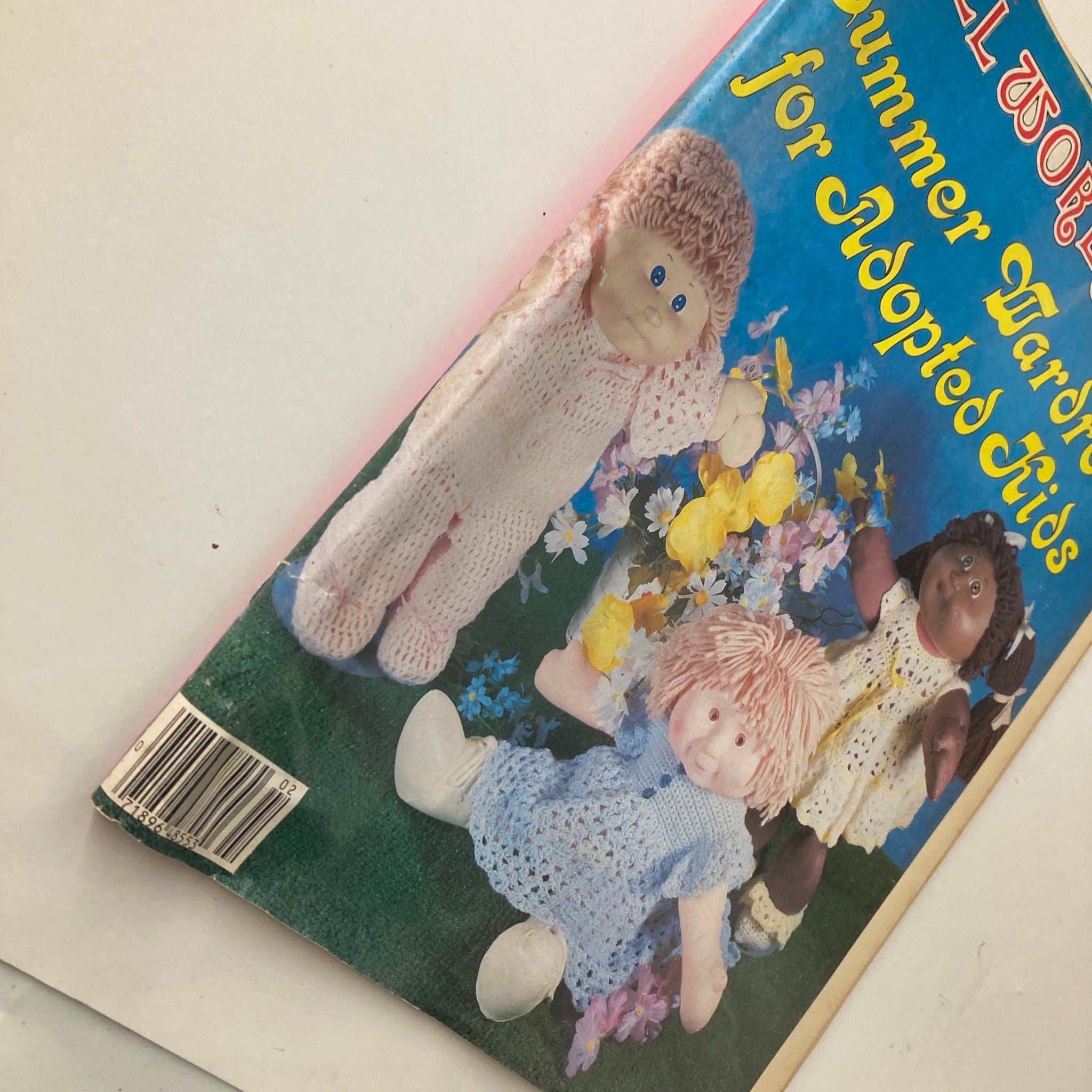 Cover of VTG Doll World Magazine 1985 #2 Summer Wardrobe for Adopted Kids featuring three dolls in colorful outfits surrounded by flowers.