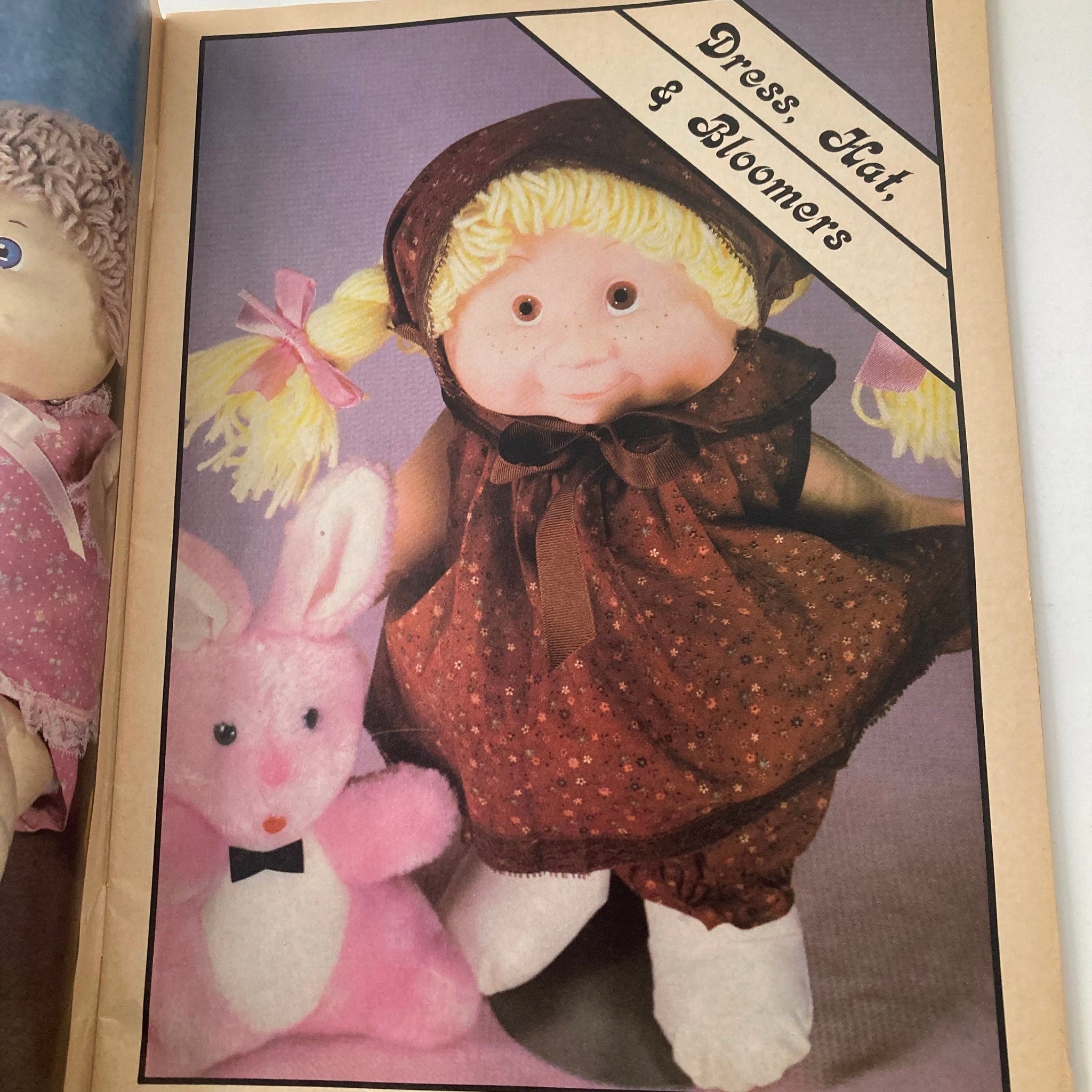 Illustration from VTG Doll World Magazine 1985 #2 featuring a doll wearing a dress, hat, and bloomers, next to a bunny toy, emphasizing summer styles for adopted kids.