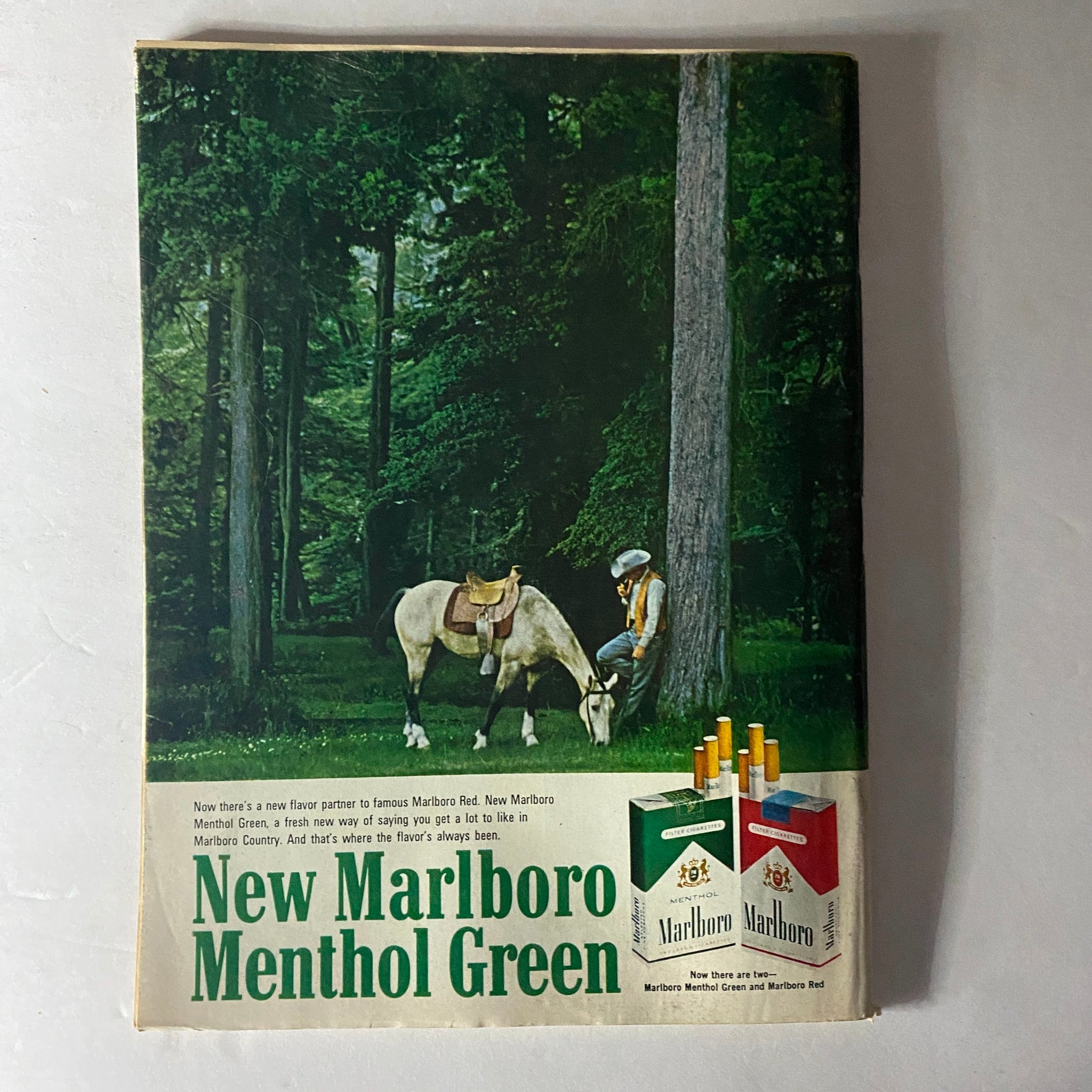 Advertisement for New Marlboro Menthol Green featured in a vintage magazine, showcasing a scene in nature with a horse and man, highlighting its promotional campaign.