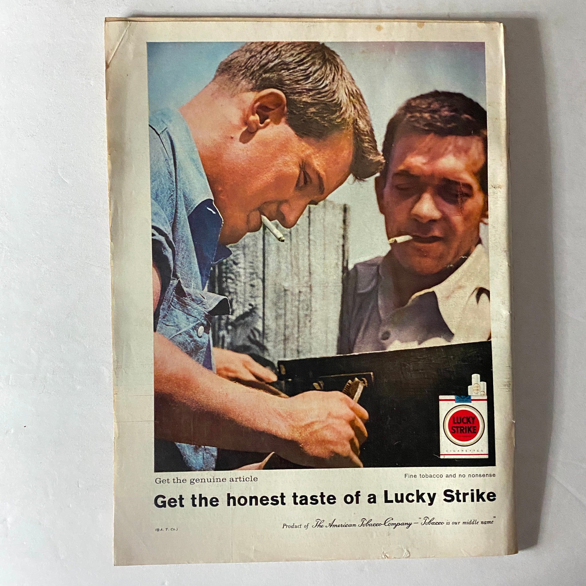 Vintage advertisement from the 1960s featuring two men smoking cigarettes, promoting Lucky Strike cigarettes, with a catchy tagline for an authentic tobacco experience.