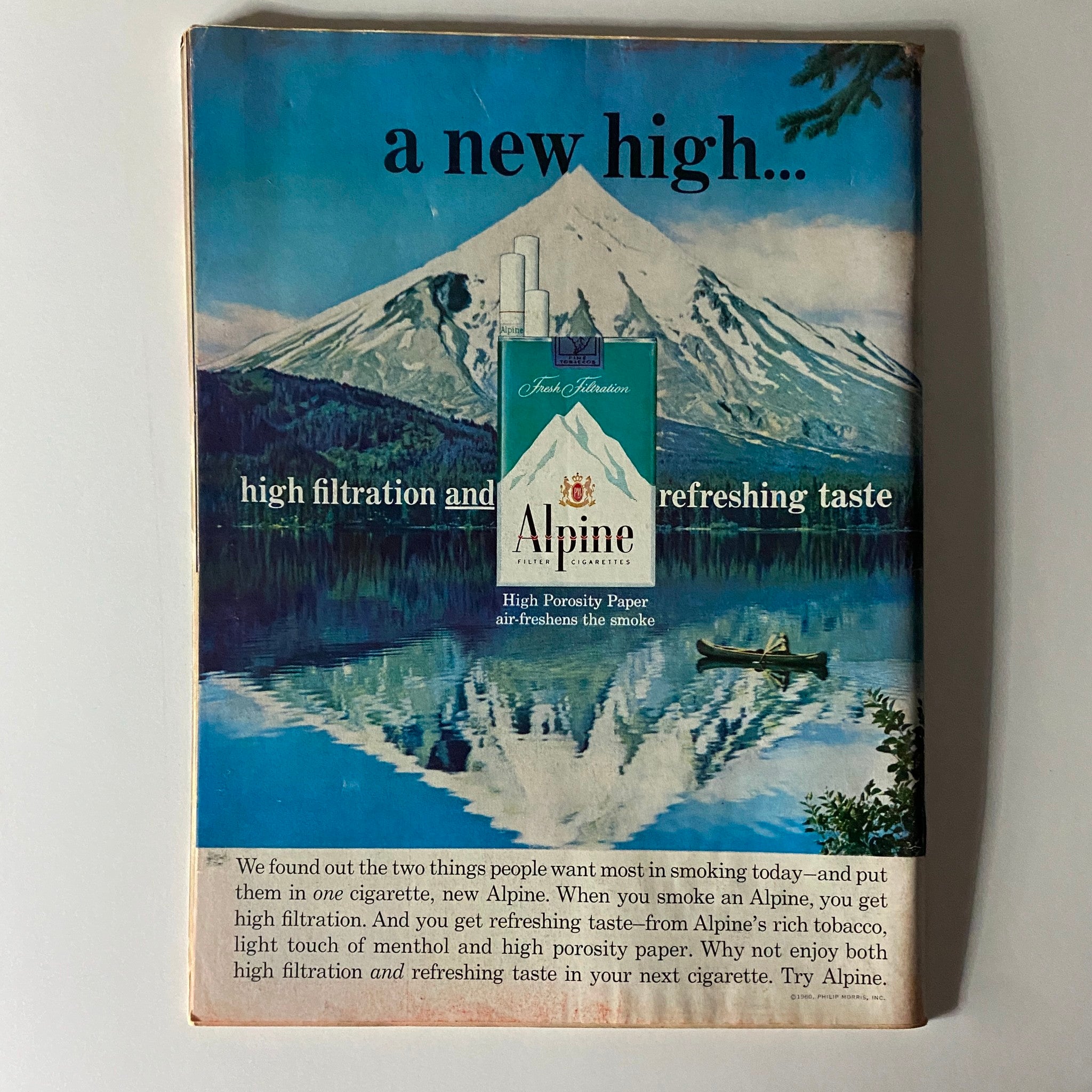 Back cover advertisement of a vintage magazine featuring the Alpine cigarette brand, showcasing a scenic mountain view and promoting high filtration and refreshing taste.