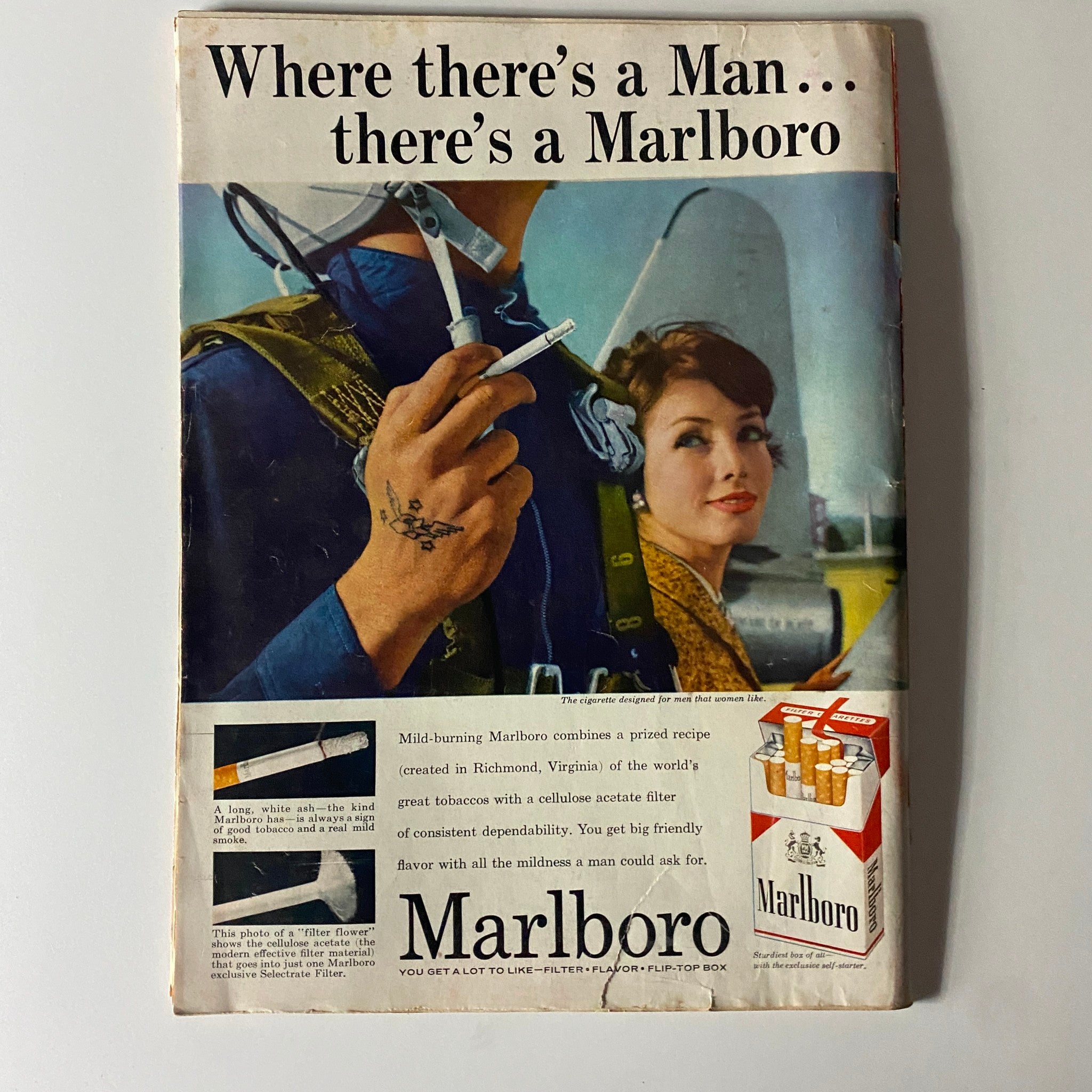 Ad for Marlboro cigarettes featuring a man dressed in military attire holding a cigarette with a woman looking on, promoting the tagline 'Where there's a Man... there's a Marlboro,' from a vintage magazine.