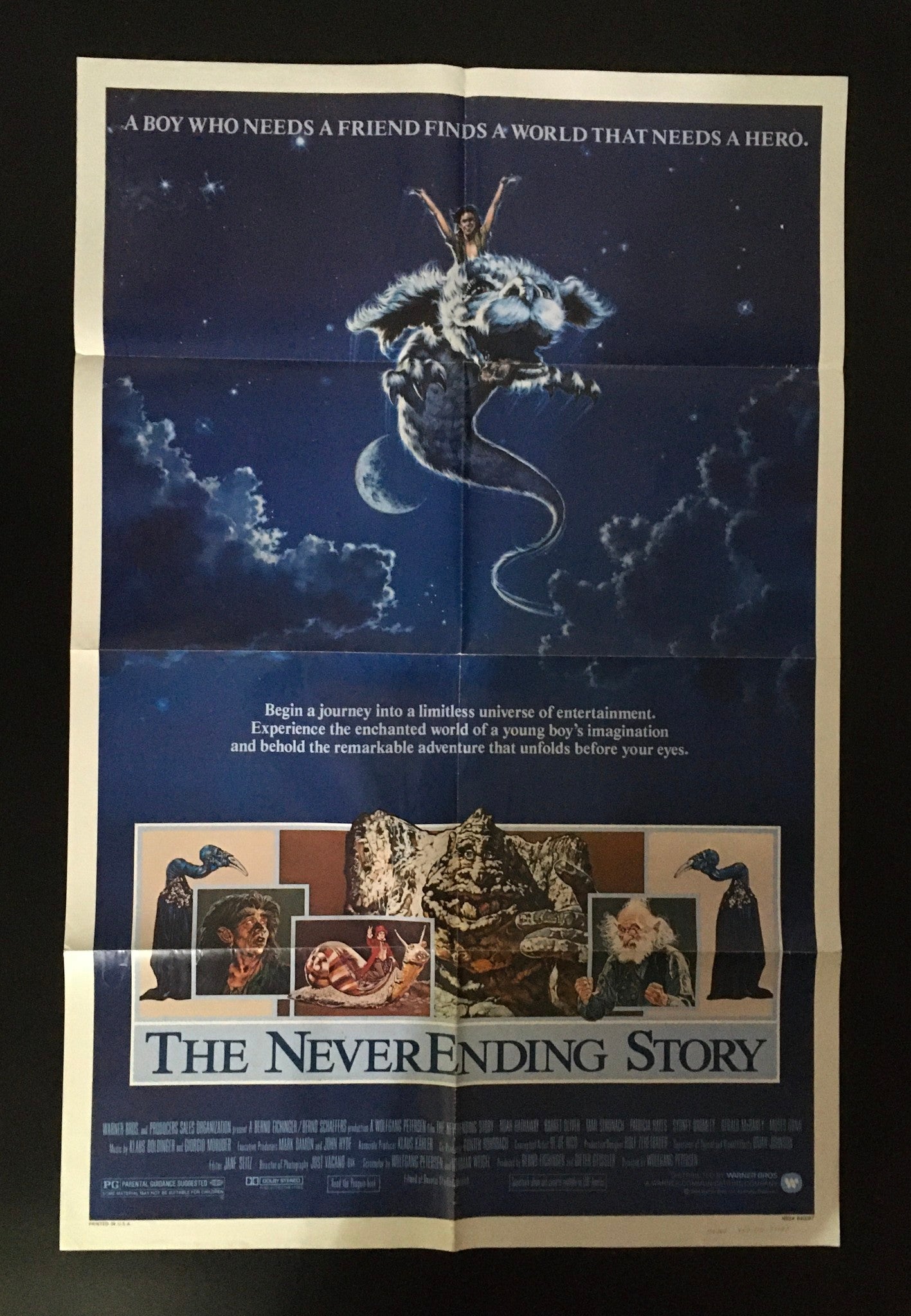 1984 The Never Ending Story 41" x 27" original movie poster featuring a boy riding a dragon-like creature under a starry sky, depicting a fantasy adventure.