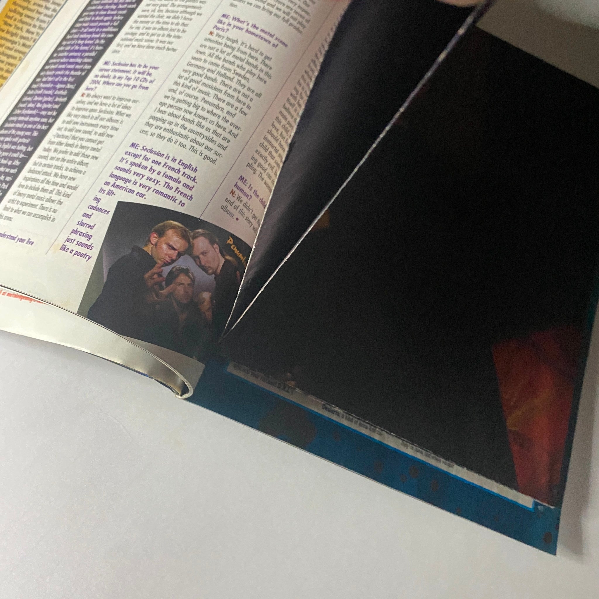 Interior image from Metal Edge Magazine May 2004, featuring a partially revealed page with a dramatic close-up, highlighting the magazine's artistic flair.