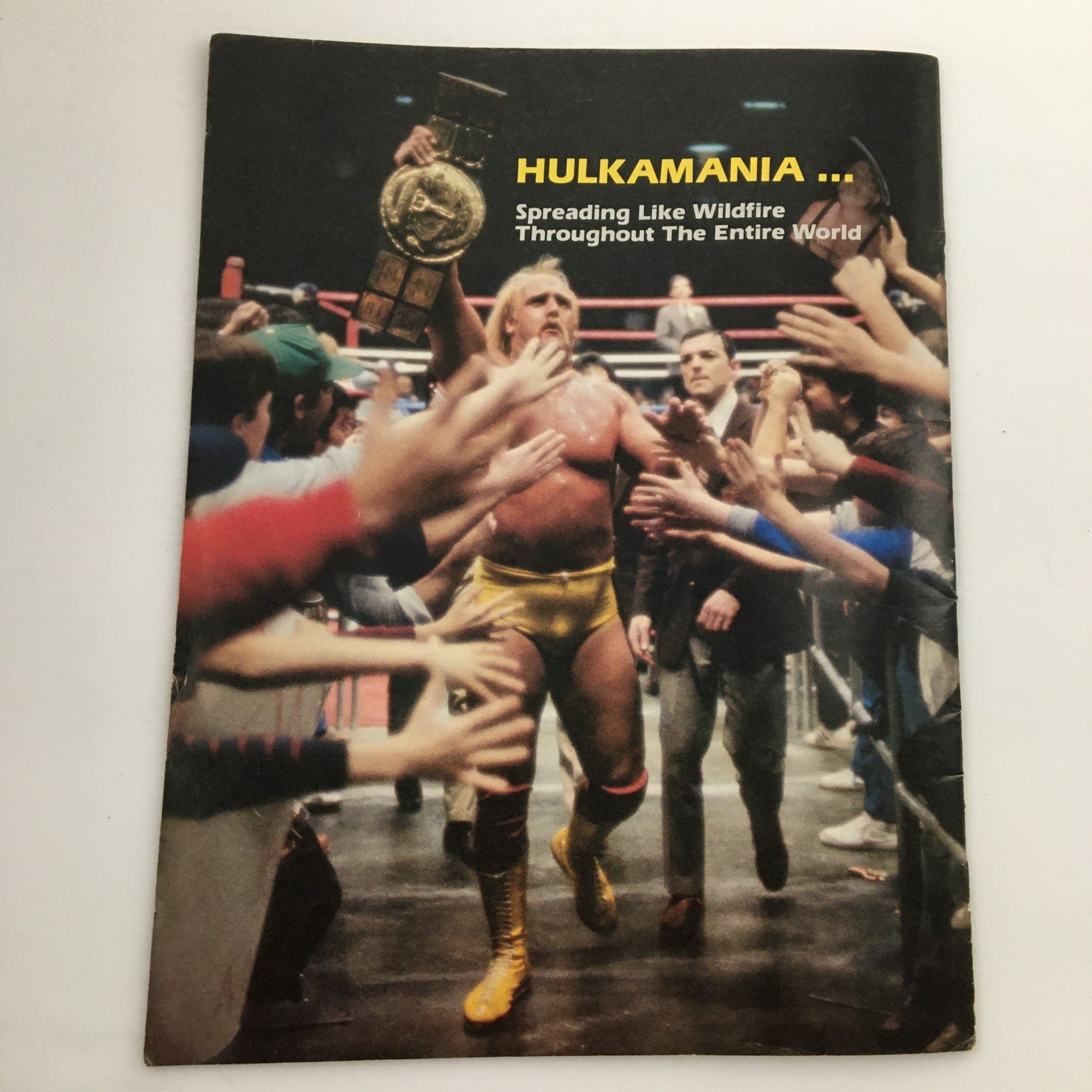 WWF Program 1984 showcasing Hulk Hogan with a championship belt, walking through cheering fans, emphasizing the 'HULKAMANIA' phenomenon.