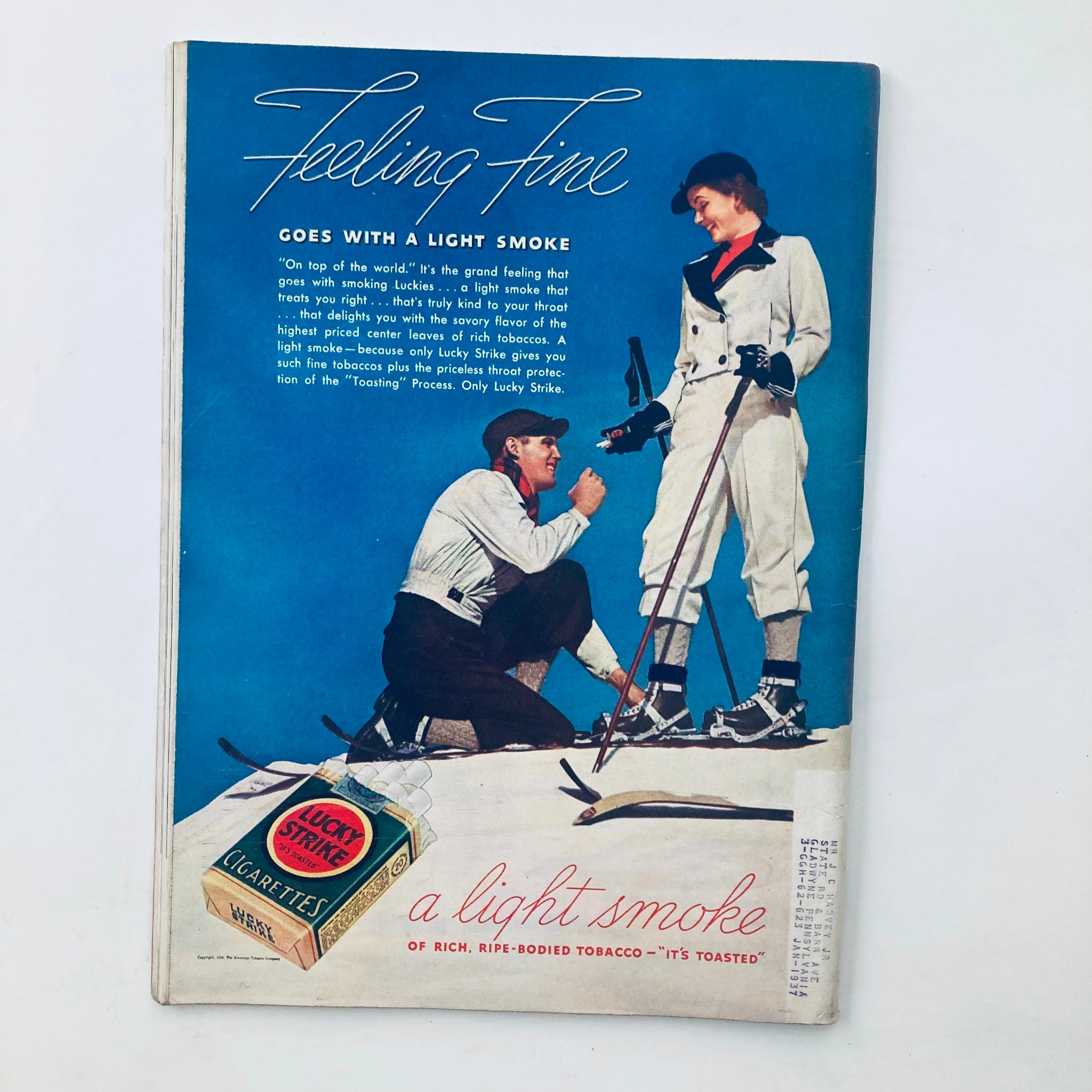 Advertisement from the back cover of a vintage magazine, promoting Lucky Strike cigarettes with the slogan 'Feeling Fine'. The blue background features a man and woman skiing, emphasizing a feeling of joy and a light smoking experience.