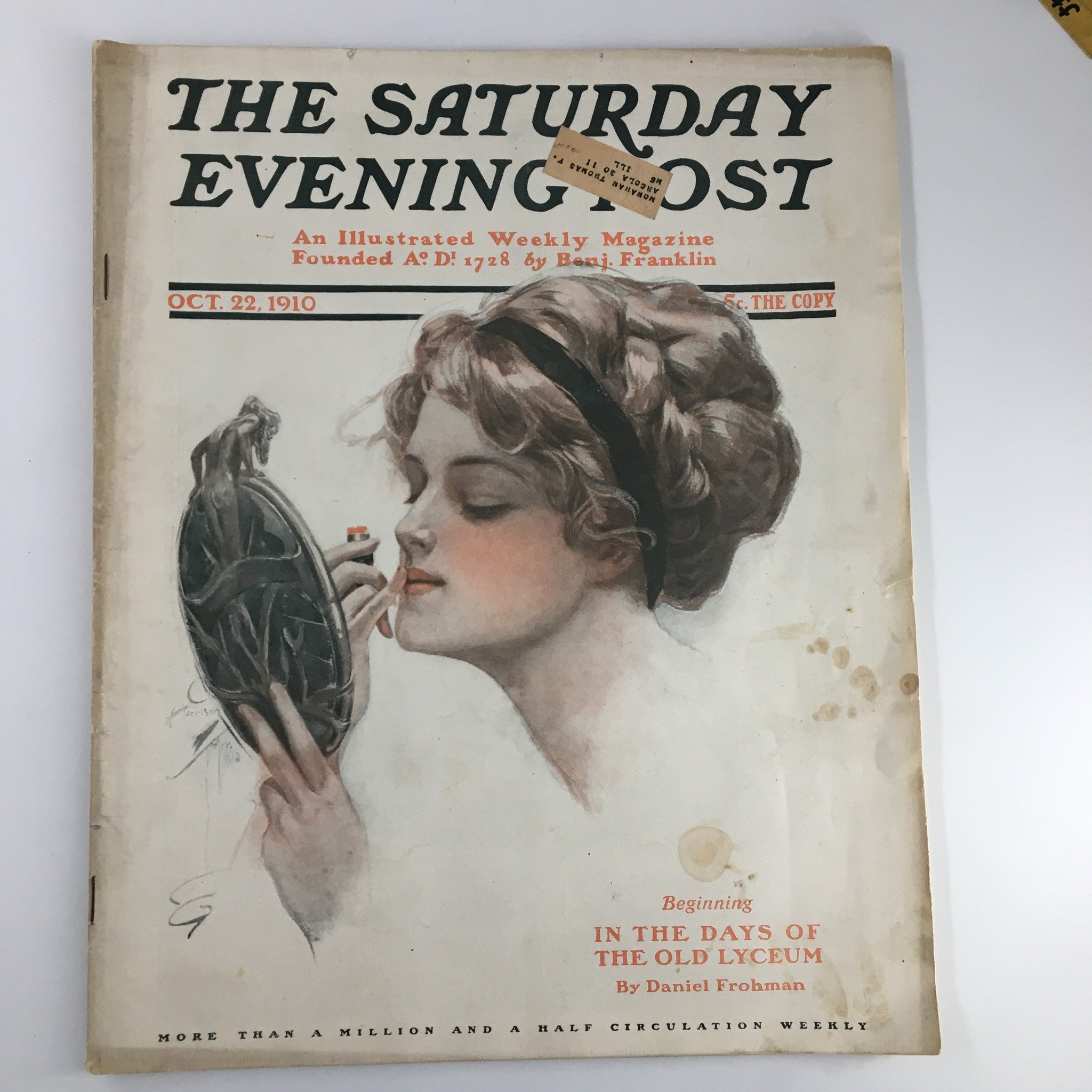 The Saturday Evening Post cover from October 22, 1910, featuring a woman gazing at a hand mirror with a stylish hairstyle, titled 'In The Days of The Old Lyceum' by Daniel Frohman.