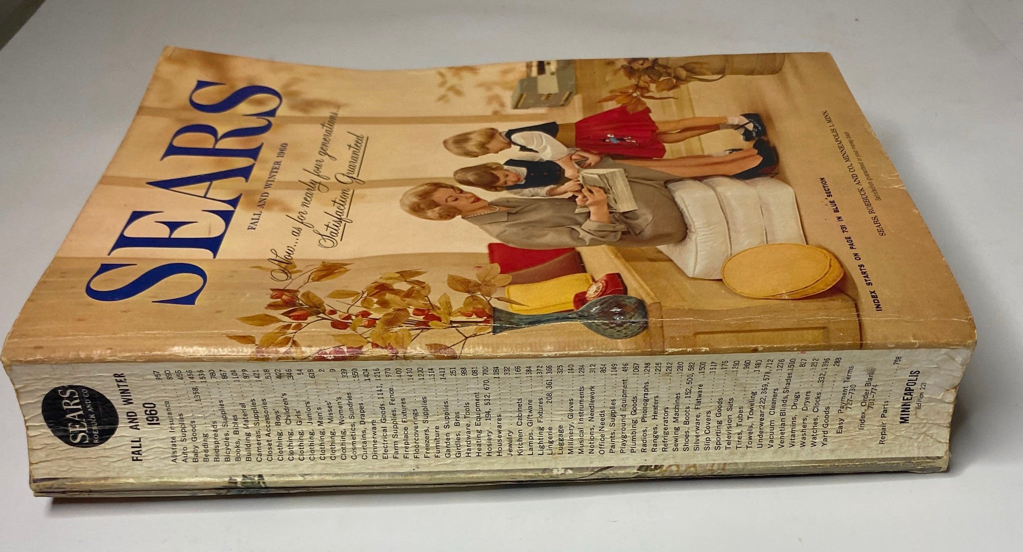 Side view of the 1960 Sears Fall and Winter Catalog, showcasing the title and illustration of a mother and children engaged with a shopping catalog.