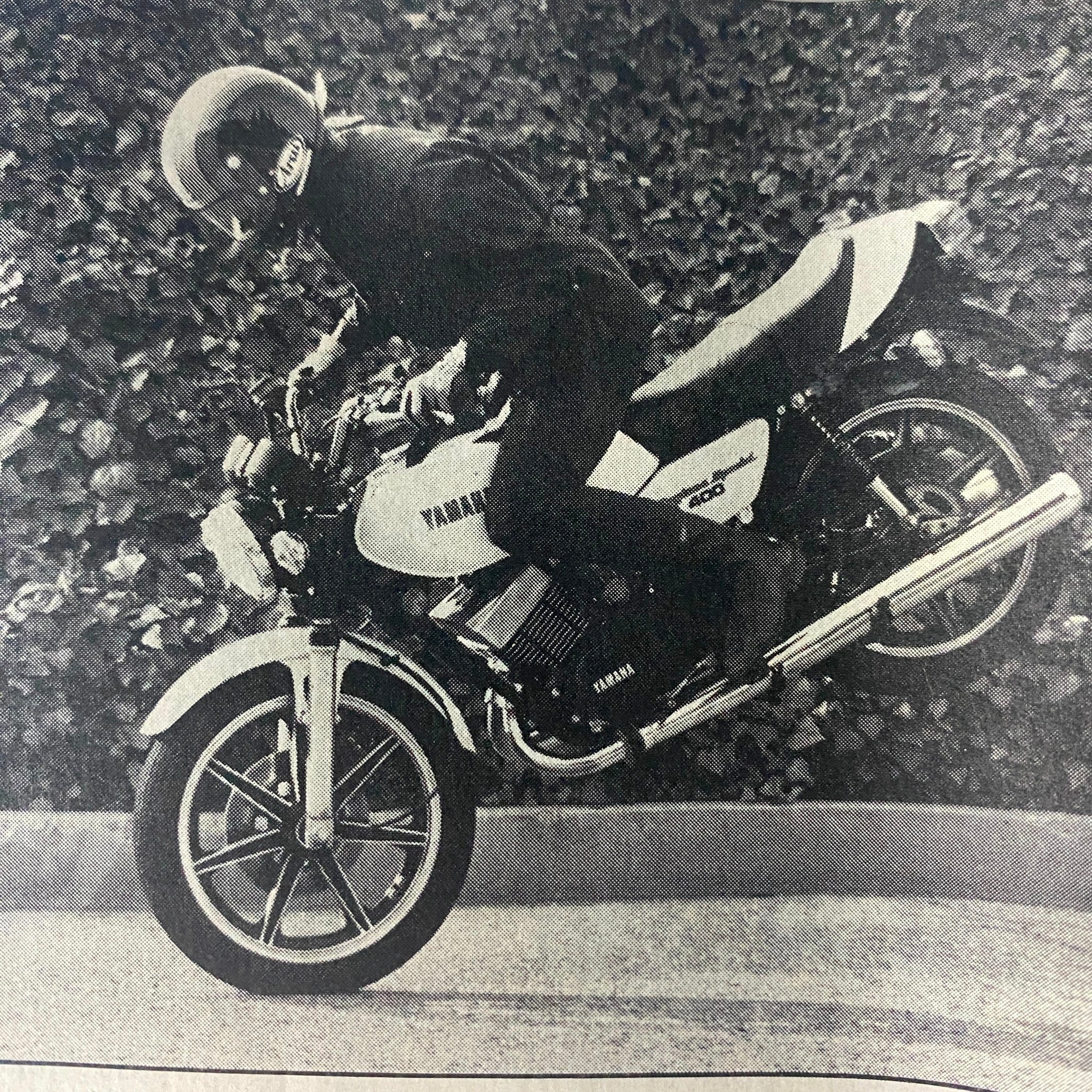 Black and white action shot of a rider performing a stunt on a Yamaha RD400 motorcycle, featured in Motorcyclist Magazine April 1979.