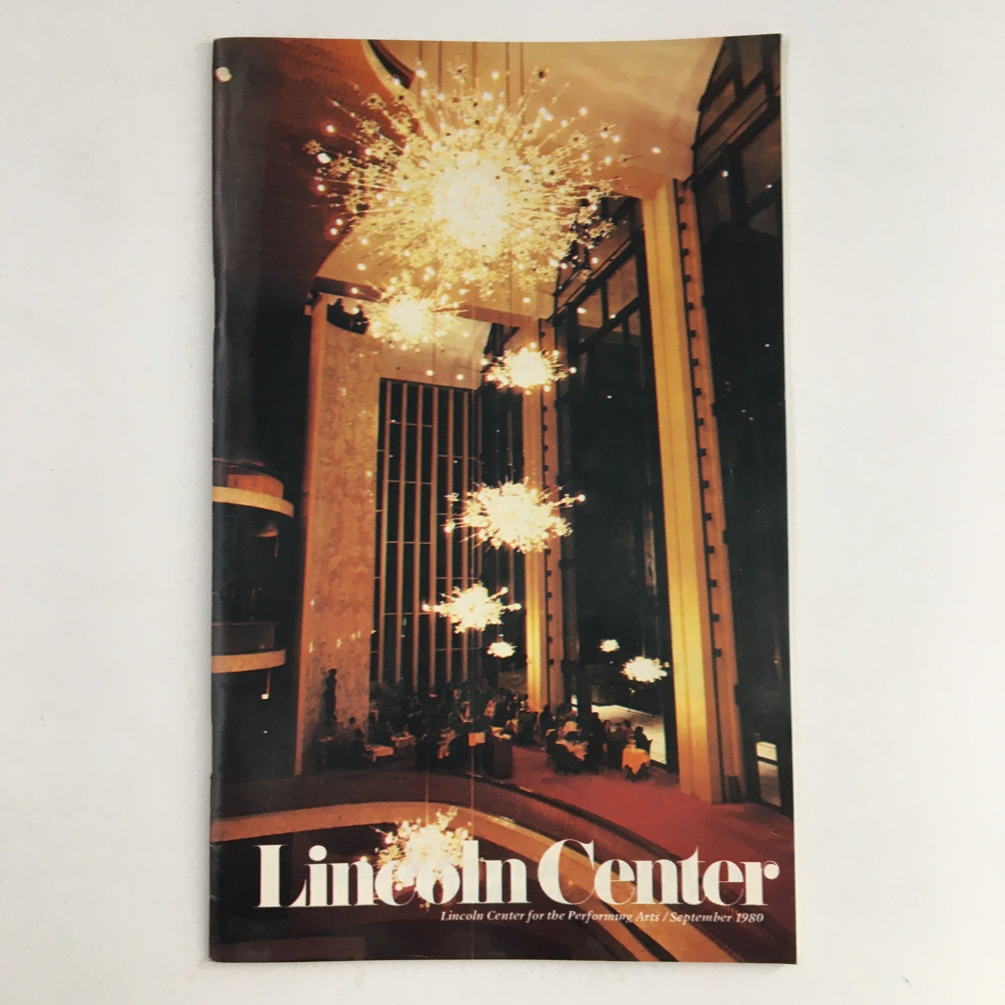 Cover of the 1980 Stagebill Lincoln Center Present The Met by William Livingstone showcasing elegant lighting fixtures within Lincoln Center, highlighting its iconic architecture.