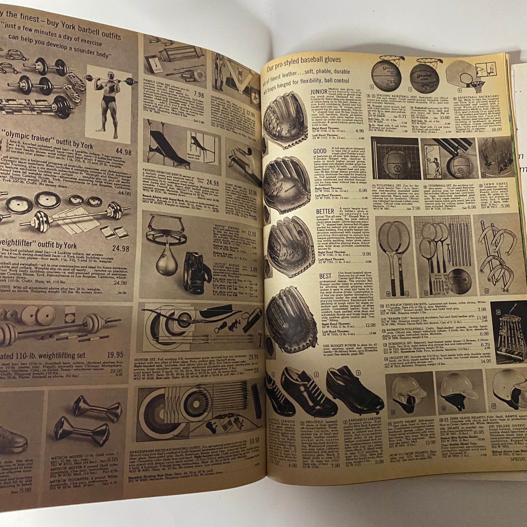 1969 Spiegel Spring and Summer Catalog page showcasing various exercise equipment including barbell outfits, Olympic trainer outfits, and weight sets, illustrating fitness trends of the late 1960s.