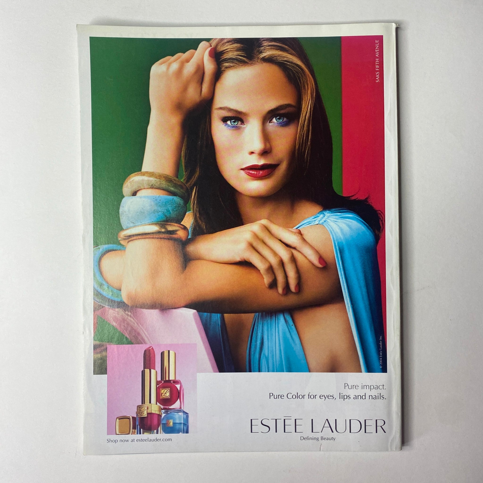Advertisment for Estée Lauder showcasing a model with vibrant makeup and accessories, promoting their Pure Color product line, featured in Vogue Magazine July 2004.