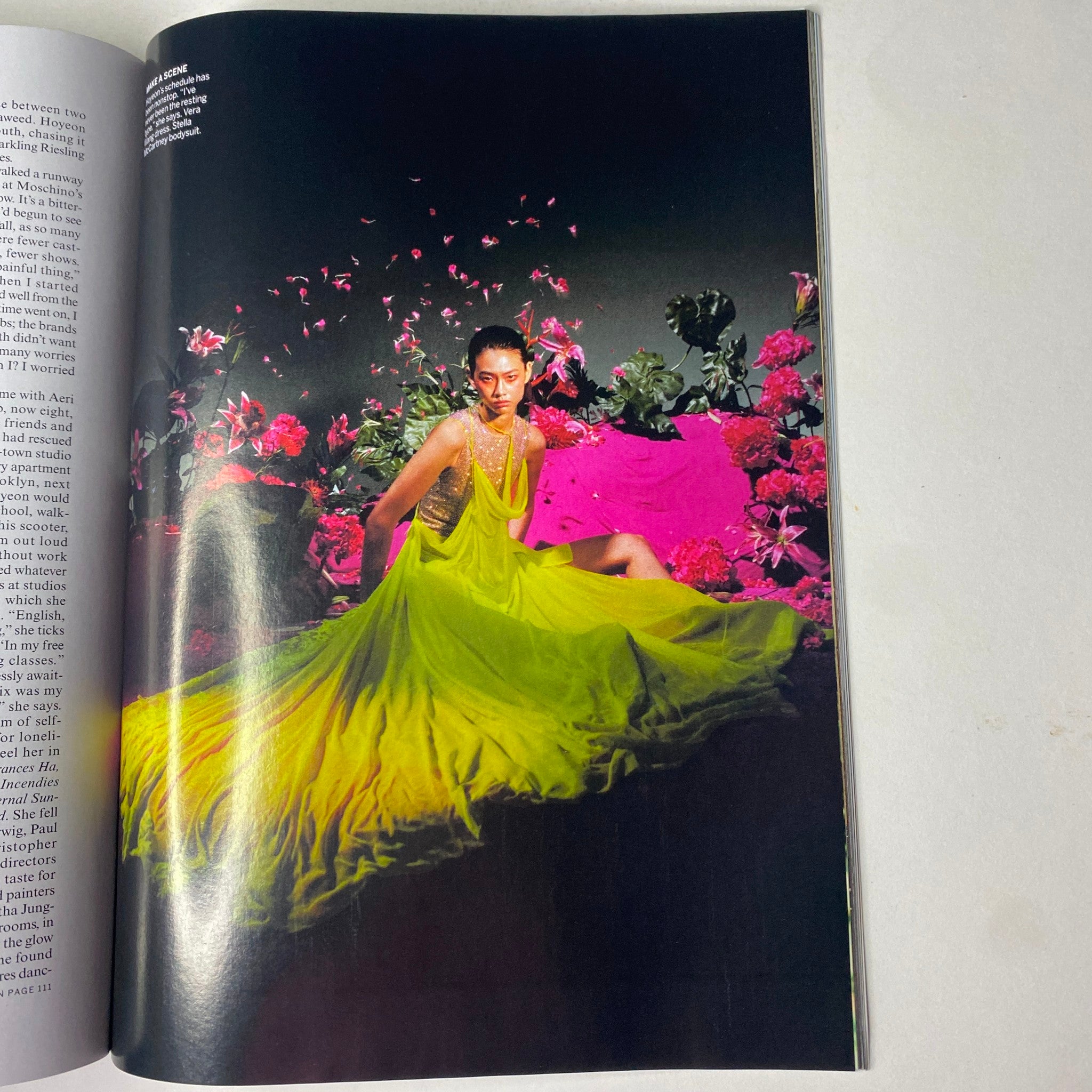 Vogue Magazine February 2022 featuring a dramatic portrait of a model in a flowing, neon green gown surrounded by colorful flowers, highlighting artistic fashion photography.