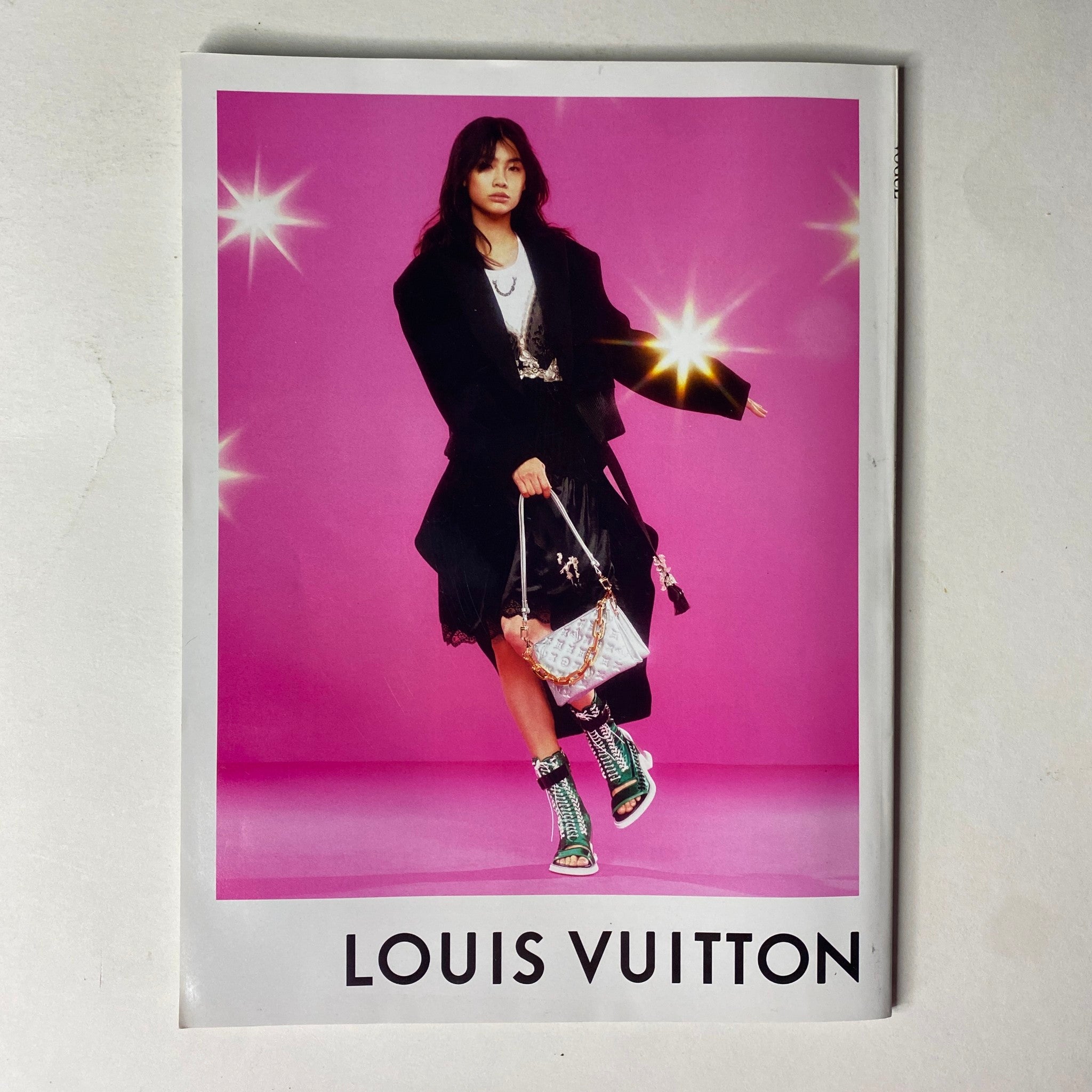Vogue Magazine February 2022 showcasing a model in a stunning black outfit against a vibrant pink background, featuring Louis Vuitton accessories in a high-fashion context.