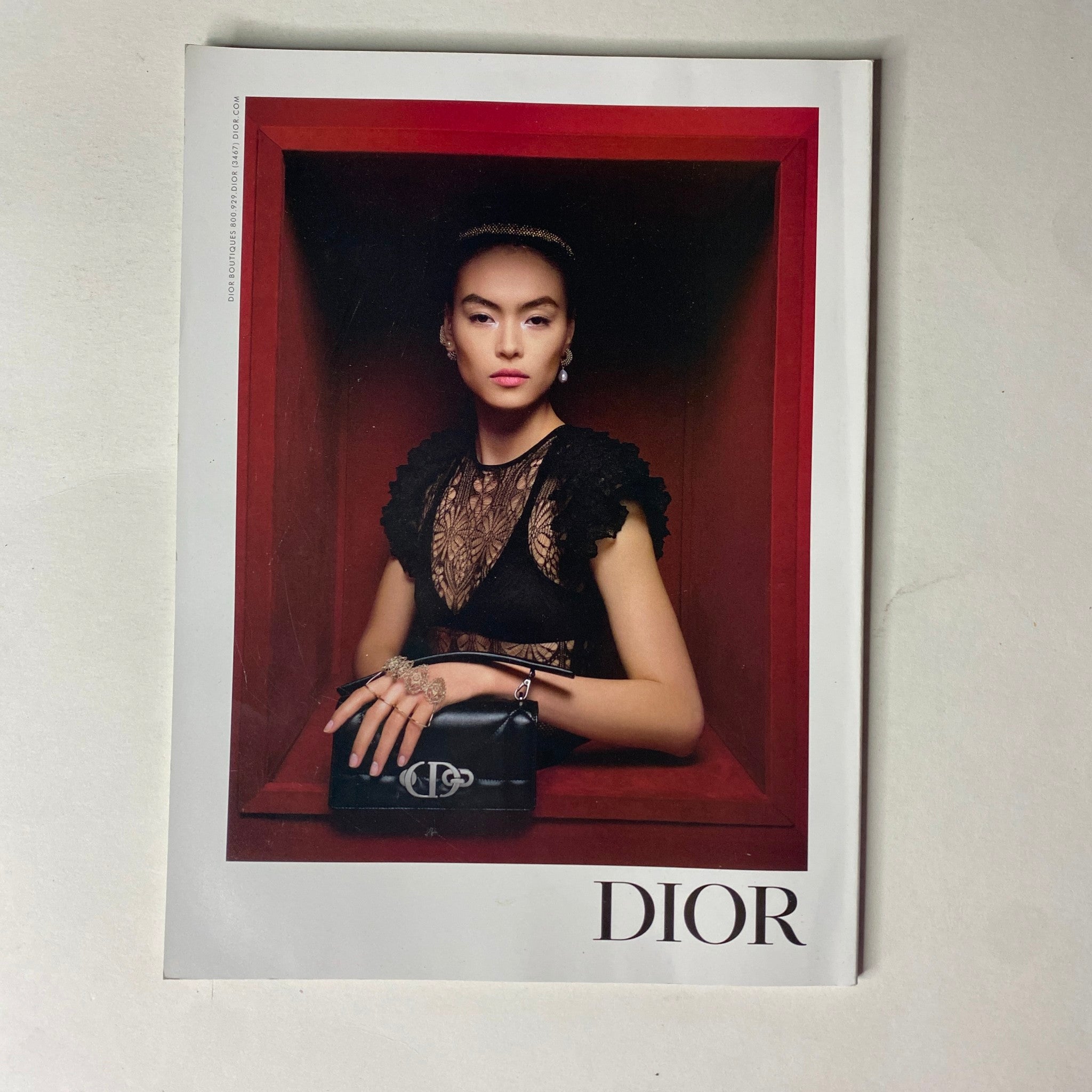 Dior advertisement from Vogue Magazine August 2022, highlighting an elegant model showcasing luxury fashion accessories in a striking setting.