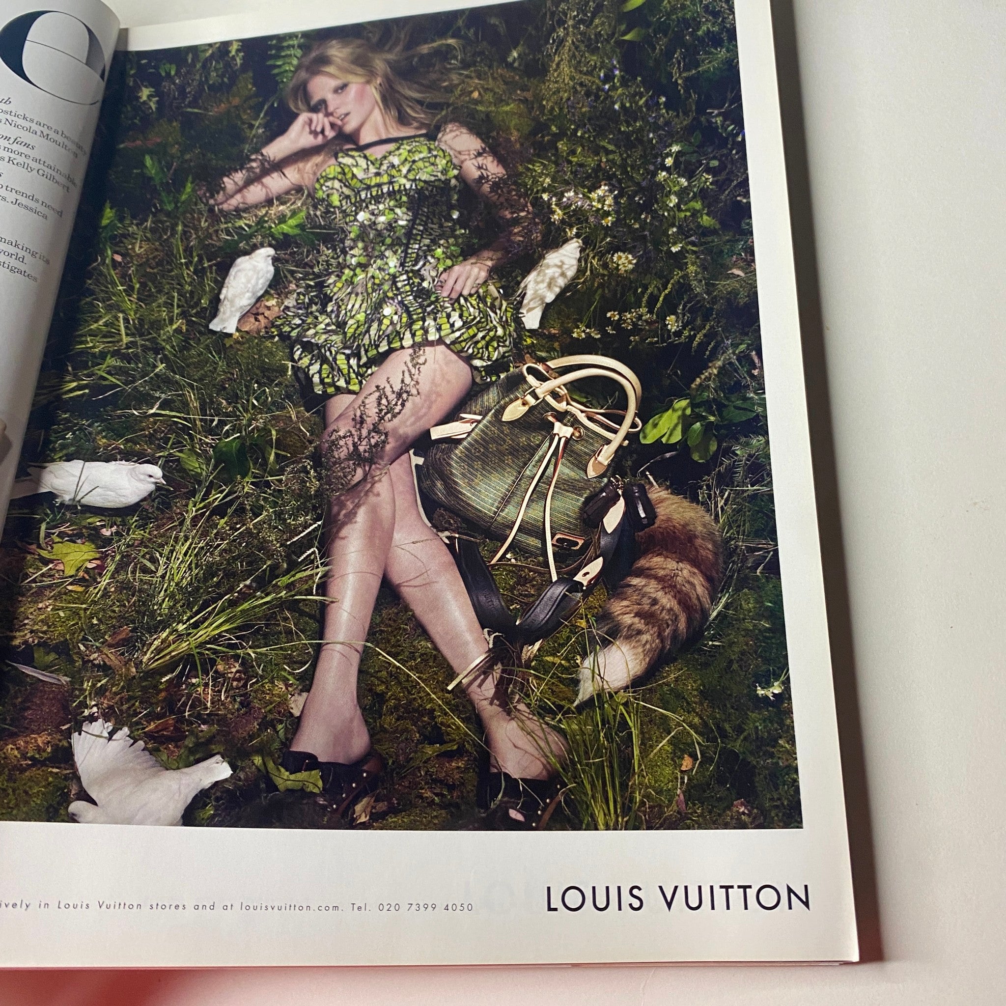 Ad page from Vogue British Magazine April 2010 featuring a Louis Vuitton model surrounded by nature and fashionable accessories.