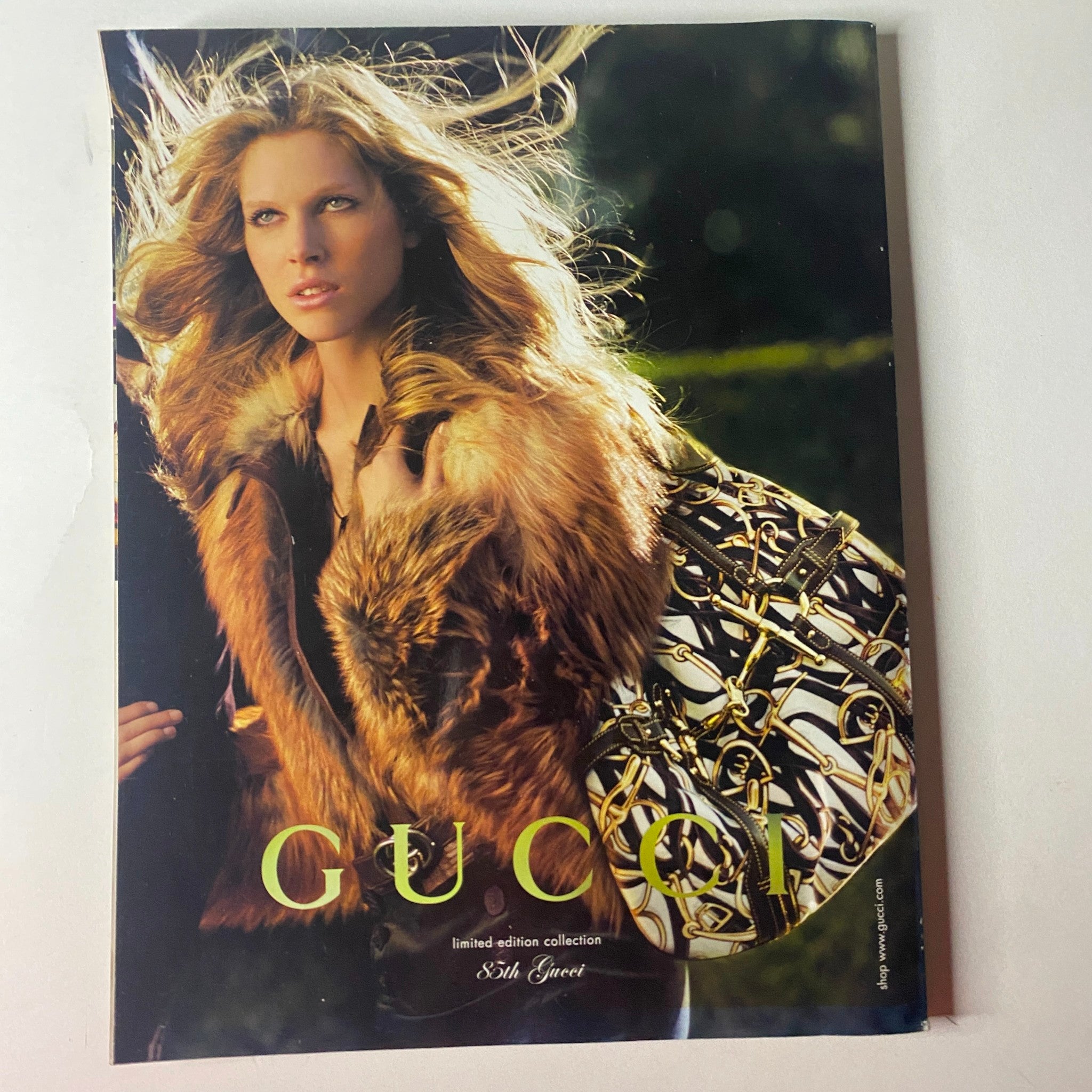 Cover page of Gucci's limited edition collection from Vogue British Magazine August 2006, featuring a model with flowing hair, wearing fur and holding an elegant handbag, embodying high fashion and luxury.