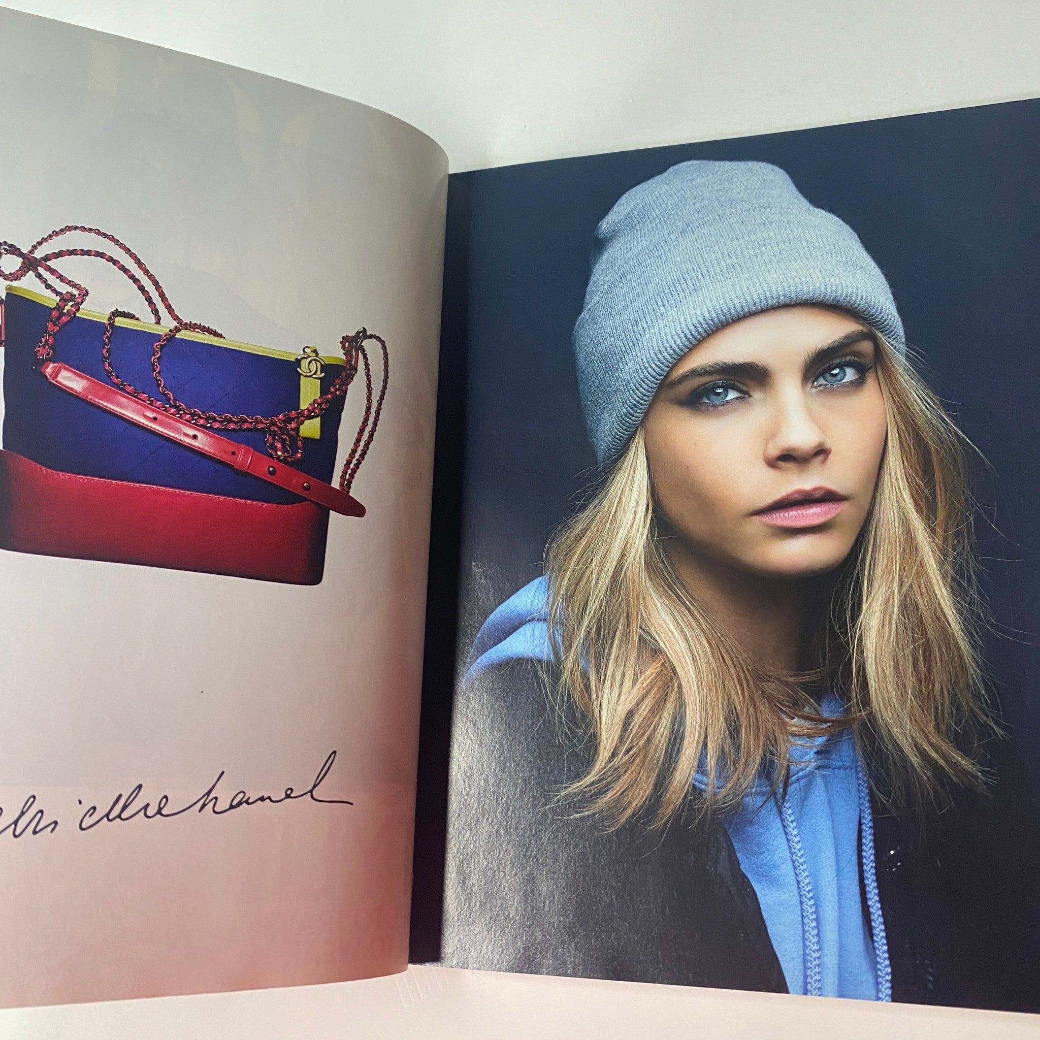 Close-up image from Vogue British Magazine June 2017 of a model with striking blue eyes wearing a beanie, alongside a colorful handbag.